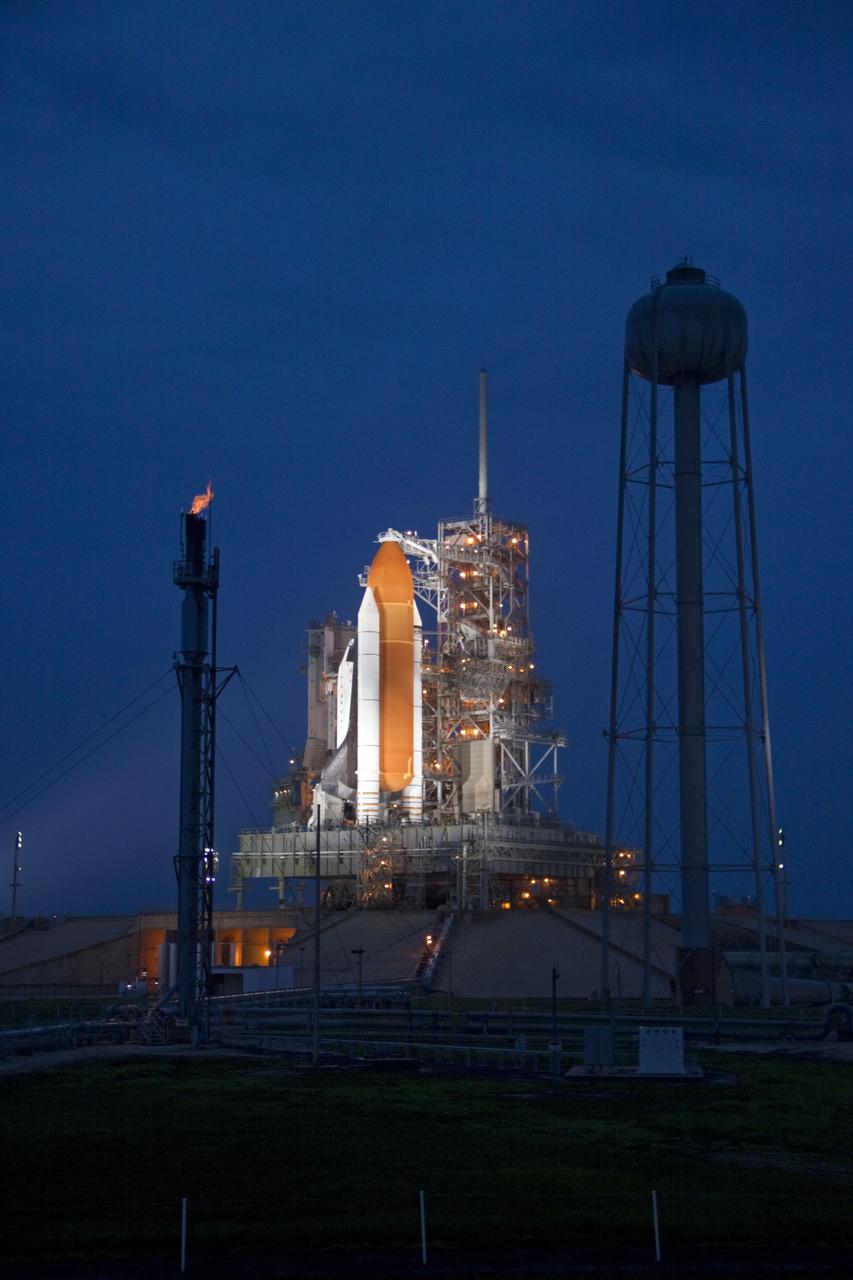 CAPE CANAVERAL, Fla. -- Space shuttle Atlantis is revealed on Launch Pad 39A at NASA's Kennedy Space Center in Florida bathed in xenon lights following the move of the rotating service structure (RSS). The structure provides weather protection and access to the shuttle while it awaits liftoff on the pad. The tower at left is used for safely burning off any excess hydrogen while the shuttle is on the pad prior to launch. To the right of the pad is the 300,000-gallon water tower that provides the water used for sound suppression on the pad during liftoff. RSS retract marks a major milestone in Atlantis' STS-135 mission countdown.              Atlantis and its crew of four; Commander Chris Ferguson, Pilot Doug Hurley, Mission Specialists Sandy Magnus and Rex Walheim will lift off at 11:26 a.m. EDT on July 8 to deliver the Raffaello multi-purpose logistics module packed with supplies and spare parts for the International Space Station. Atlantis also will fly the Robotic Refueling Mission experiment that will investigate the potential for robotically refueling existing satellites in orbit. In addition, Atlantis will return with a failed ammonia pump module to help NASA better understand the failure mechanism and improve pump designs for future systems. STS-135 is the 33rd flight of Atlantis, the 37th shuttle mission to the space station, and the 135th and final mission of NASA's Space Shuttle Program. For more information, visit www.nasa.gov/mission_pages/shuttle/shuttlemissions/sts135/index.html. Photo credit: Jim Grossmann