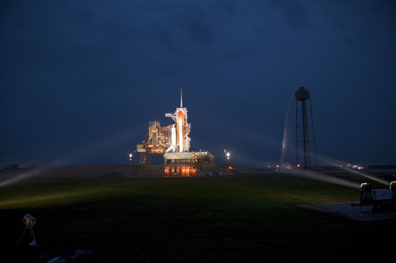CAPE CANAVERAL, Fla. -- Space shuttle Atlantis is revealed on Launch Pad 39A at NASA's Kennedy Space Center in Florida bathed in xenon lights following the move of the rotating service structure (RSS). The structure provides weather protection and access to the shuttle while it awaits liftoff on the pad.  To the right of the pad is the 300,000-gallon water tower that provides the water used for sound suppression on the pad during liftoff. RSS retract marks a major milestone in Atlantis' STS-135 mission countdown.              Atlantis and its crew of four; Commander Chris Ferguson, Pilot Doug Hurley, Mission Specialists Sandy Magnus and Rex Walheim will lift off at 11:26 a.m. EDT on July 8 to deliver the Raffaello multi-purpose logistics module packed with supplies and spare parts for the International Space Station. Atlantis also will fly the Robotic Refueling Mission experiment that will investigate the potential for robotically refueling existing satellites in orbit. In addition, Atlantis will return with a failed ammonia pump module to help NASA better understand the failure mechanism and improve pump designs for future systems. STS-135 is the 33rd flight of Atlantis, the 37th shuttle mission to the space station, and the 135th and final mission of NASA's Space Shuttle Program. For more information, visit www.nasa.gov/mission_pages/shuttle/shuttlemissions/sts135/index.html. Photo credit: Jim Grossmann