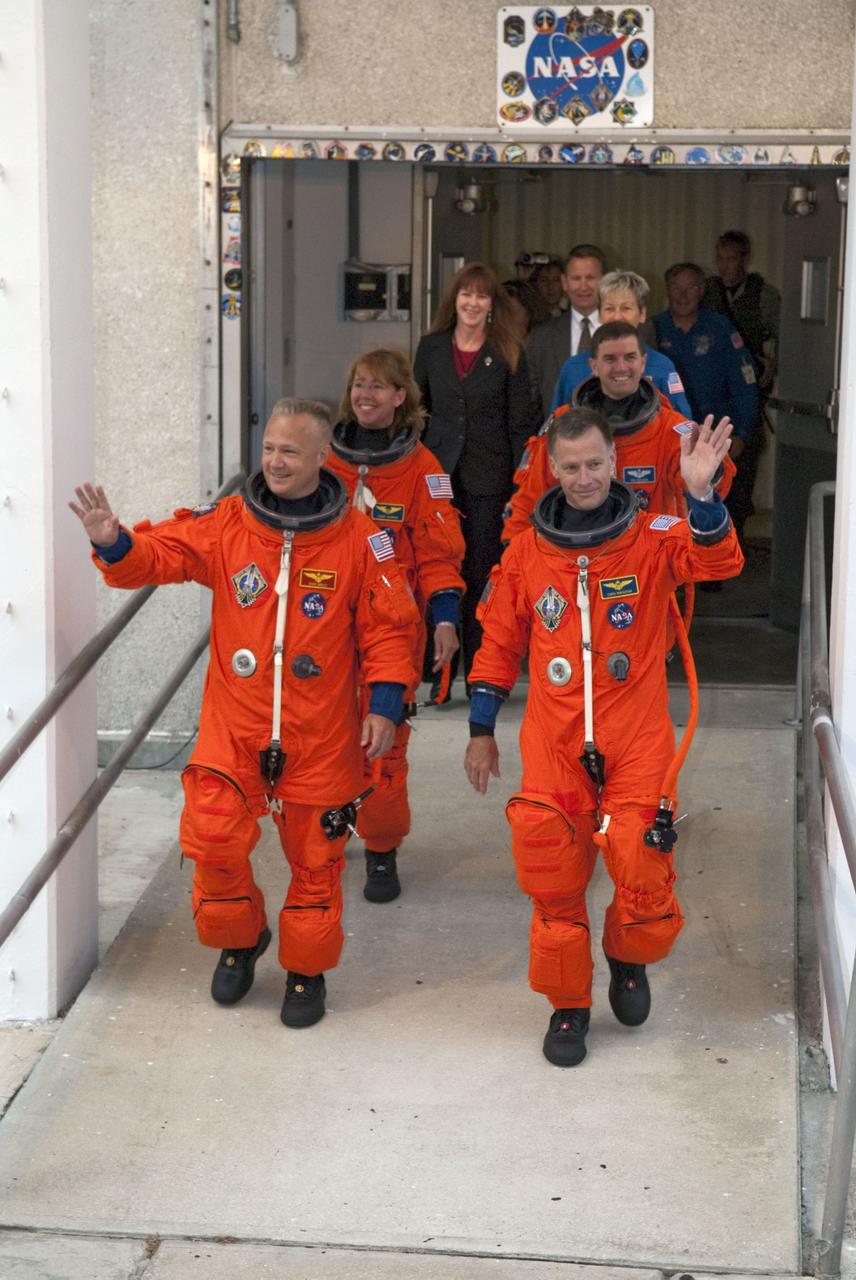 CAPE CANAVERAL, Fla. -- Dressed in their bright-orange launch-and-entry suits, the final four astronauts to launch aboard a space shuttle exit the Astronaut Crew Quarters in the Operations and Checkout Building at NASA's Kennedy Space Center in Florida. In the left row, STS-135 Pilot Doug Hurley is followed by Mission Specialist Sandy Magnus. In the right row, Commander Chris Ferguson is followed by Mission Specialist Rex Walheim. The astronauts, who will head to Launch Pad 39A aboard the silver Astrovan, are scheduled to lift off aboard space shuttle Atlantis at 11:26 a.m. EDT on July 8 for their mission to the International Space Station.    STS-135 will deliver the Raffaello multi-purpose logistics module packed with supplies and spare parts for the orbiting outpost. Atlantis also will fly the Robotic Refueling Mission experiment that will investigate the potential for robotically refueling existing satellites in orbit. In addition, Atlantis will return with a failed ammonia pump module to help NASA better understand the failure mechanism and improve pump designs for future systems. STS-135 will be the 33rd flight of Atlantis, the 37th shuttle mission to the space station, and the 135th and final mission of NASA's Space Shuttle Program. For more information, visit www.nasa.gov/mission_pages/shuttle/shuttlemissions/sts135/index.html. Photo credit: NASA/Kim Shiflett