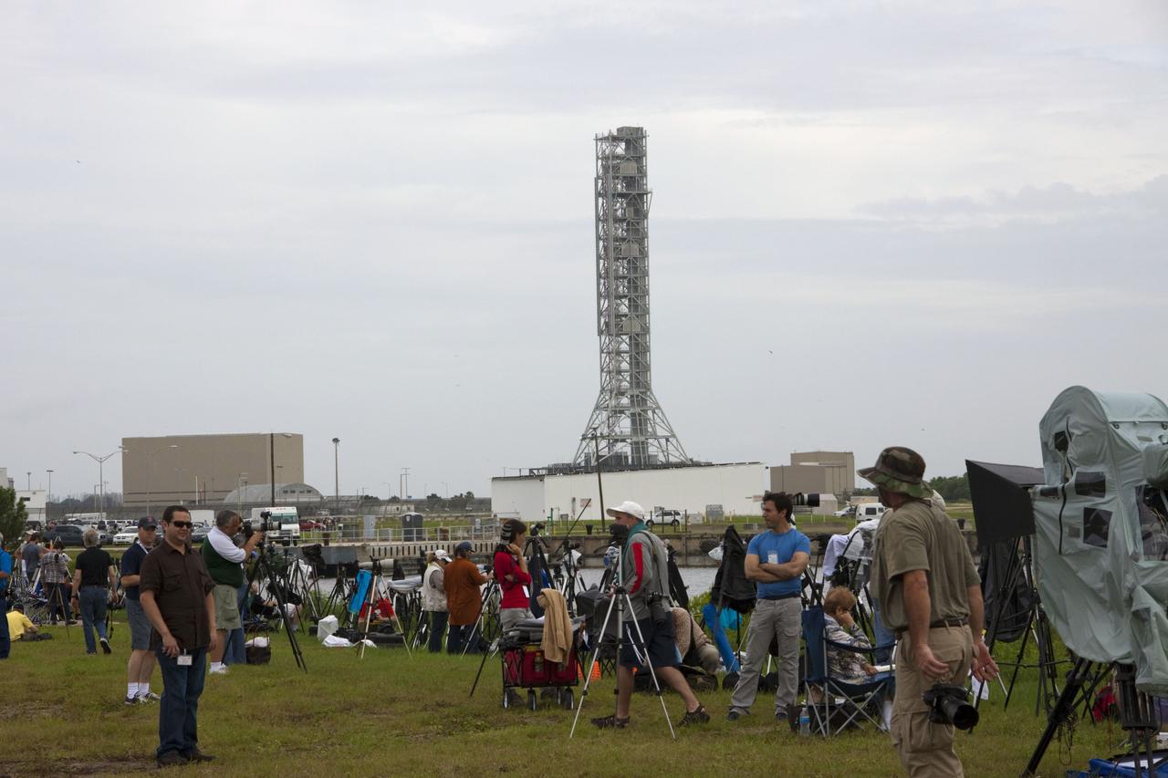 CAPE CANAVERAL, Fla. -- Media from around the globe gather at the NASA News Center at NASA Kennedy Space Center's Press Site in Florida to photograph and cover the prelaunch activities and lift off of space shuttle Atlantis on its STS-135 mission to the International Space Station. Seen in the background is NASA's new mobile launcher (ML) support structure. The ML can be outfitted with ground support equipment, such as umbilicals and access arms, for future rocket launches.                 Atlantis began its final flight, with Commander Chris Ferguson, Pilot Doug Hurley and Mission Specialists Sandy Magnus and Rex Walheim on board, at 11:29 a.m. EDT July 8 to deliver the Raffaello multi-purpose logistics module packed with supplies and spare parts to the station. Also in Atlantis' payload bay is the Robotic Refueling Mission experiment that will investigate the potential for robotically refueling existing satellites in orbit. In addition, Atlantis will return with a failed ammonia pump module to help NASA better understand the failure mechanism and improve pump designs for future systems. STS-135 is the 33rd flight of Atlantis, the 37th shuttle mission to the space station, and the 135th and final mission of NASA's Space Shuttle Program. For more information, visit www.nasa.gov/mission_pages/shuttle/shuttlemissions/sts135/index.html. Photo credit: NASA/Jim Grossmann