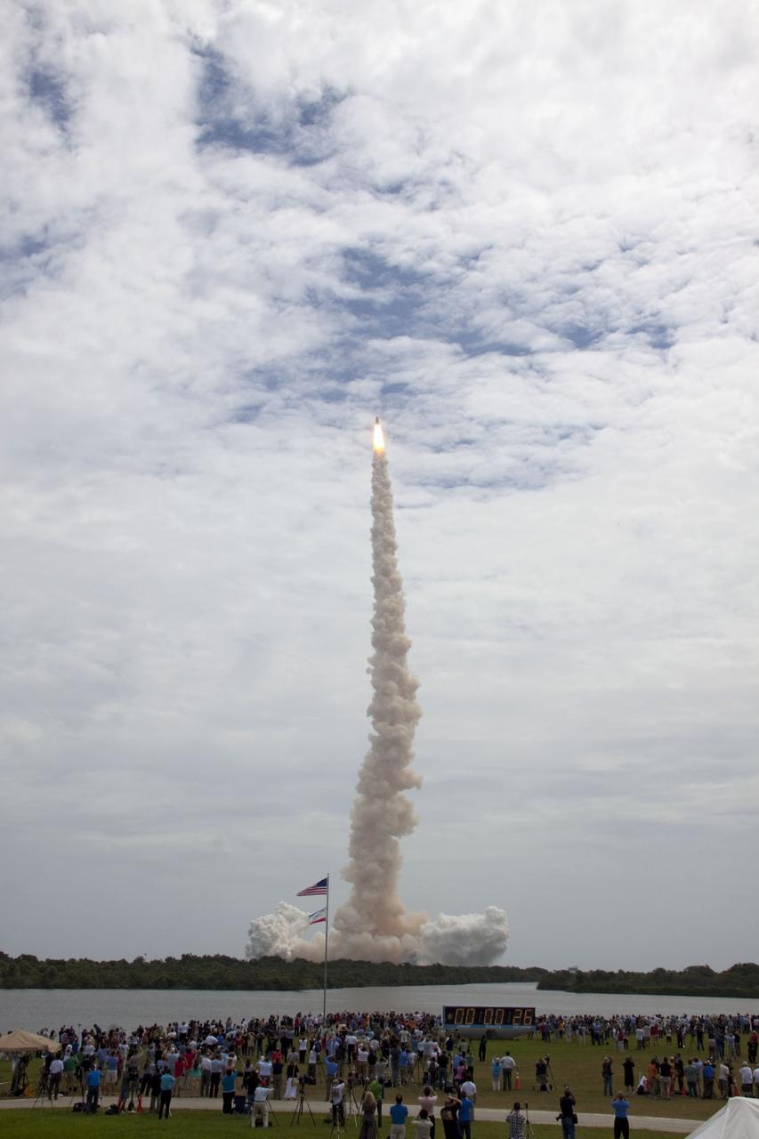 CAPE CANAVERAL, Fla. -- Members of the media and employees gather near the countdown clock to see space shuttle Atlantis soar toward space after lifting off Launch Pad 39A at NASA's Kennedy Space Center in Florida at 11:29 a.m. EDT on July 8. On board are four experienced astronauts -- STS-135 Commander Chris Ferguson, Pilot Doug Hurley, and Mission Specialists Sandy Magnus and Rex Walheim.        STS-135 will deliver the Raffaello multi-purpose logistics module packed with supplies and spare parts for the International Space Station. Atlantis also will fly the Robotic Refueling Mission experiment that will investigate the potential for robotically refueling existing satellites in orbit. In addition, Atlantis will return with a failed ammonia pump module to help NASA better understand the failure mechanism and improve pump designs for future systems. STS-135 will be the 33rd flight of Atlantis, the 37th shuttle mission to the space station, and the 135th and final mission of NASA's Space Shuttle Program. For more information, visit www.nasa.gov/mission_pages/shuttle/shuttlemissions/sts135/index.html. Photo credit: NASA/Jim Grossmann