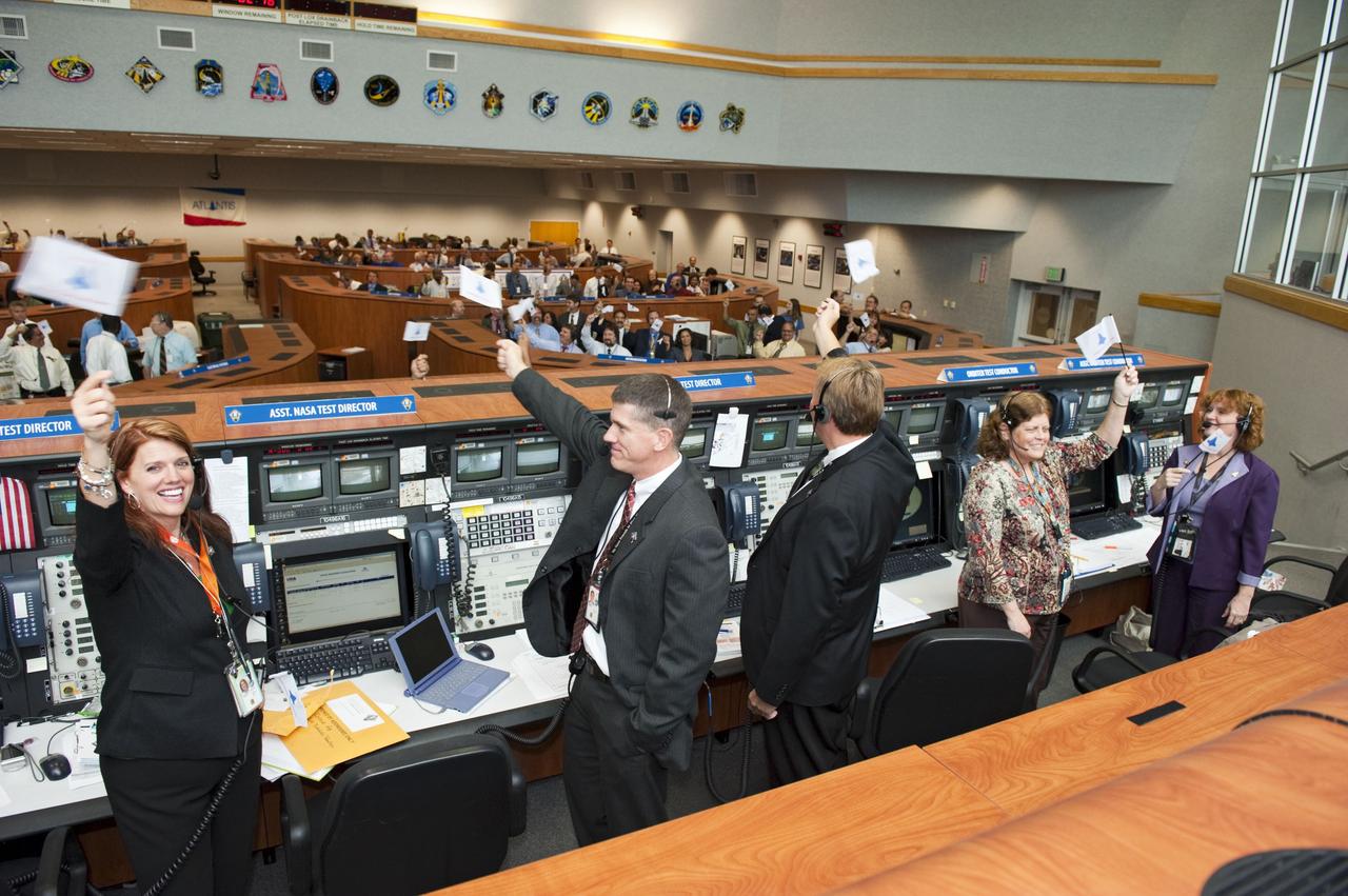 CAPE CANAVERAL, Fla. -- Launch controllers wave their STS-135 shuttle launch team member flags and cheer in Firing Room 4 of the Launch Control Center following the successful launch of space shuttle Atlantis from NASA's Kennedy Space Center in Florida. In the foreground, from left, are NASA Test Directors Charlie Blackwell-Thompson, Jeremy Graeber, and Jeff Spaulding; Orbiter Test Conductor Roberta Wyrick; and Assistant Orbiter Test Conductor Laurie Sally. Atlantis began its final flight, the STS-135 mission to the International Space Station, at 11:29 a.m. EDT on July 8. STS-135 will deliver the Raffaello multi-purpose logistics module packed with supplies and spare parts for the International Space Station. Atlantis also is flying the Robotic Refueling Mission experiment that will investigate the potential for robotically refueling existing satellites in orbit. In addition, Atlantis will return with a failed ammonia pump module to help NASA better understand the failure mechanism and improve pump designs for future systems. STS-135 is the 33rd flight of Atlantis, the 37th shuttle mission to the space station, and the 135th and final mission of NASA's Space Shuttle Program. For more information, visit www.nasa.gov/mission_pages/shuttle/shuttlemissions/sts135/index.html. Photo credit: NASA/Kim Shiflett