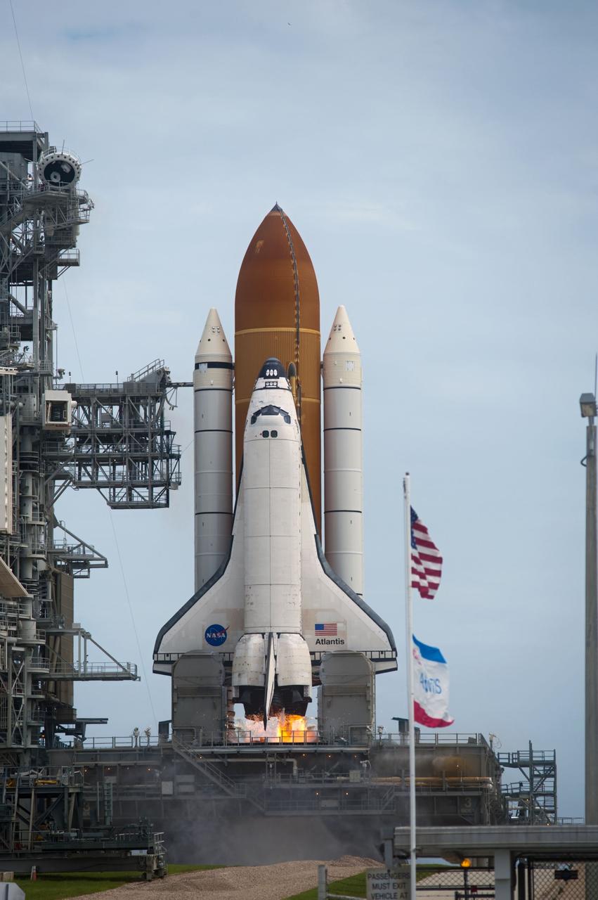 CAPE CANAVERAL, Fla. -- Flags on Launch Pad 39A at NASA's Kennedy Space Center in Florida wave a final salute to space shuttle Atlantis as its engines ignite for liftoff.  Atlantis began its final flight, the STS-135 mission to the International Space Station, at 11:29 a.m. EDT July 8.    STS-135 will deliver the Raffaello multi-purpose logistics module packed with supplies and spare parts to the orbiting laboratory. Atlantis also is flying the Robotic Refueling Mission experiment that will investigate the potential for robotically refueling existing satellites in orbit. In addition, a failed ammonia pump module will be returned to Earth aboard Atlantis to help NASA better understand the failure mechanism and improve pump designs for future systems. STS-135 is the 33rd flight of Atlantis, the 37th shuttle mission to the space station, and the 135th and final mission of NASA's Space Shuttle Program. For more information, visit www.nasa.gov/mission_pages/shuttle/shuttlemissions/sts135/index.html. Photo credit: NASA/Tony Gray and Tom Farrar