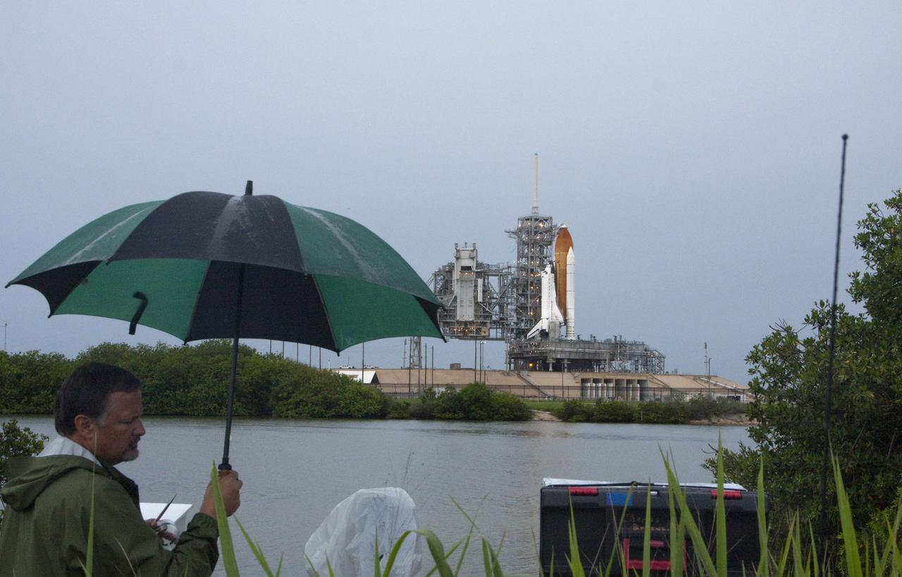 CAPE CANAVERAL, Fla. -- At NASA's Kennedy Space Center, space shuttle Atlantis can be seen in the distance awaiting liftoff on its STS-135 mission while members of the media set up cameras to capture the launch on a very rainy day in Florida.    Atlantis and its crew of four; Commander Chris Ferguson, Pilot Doug Hurley, Mission Specialists Sandy Magnus and Rex Walheim are scheduled to lift off at 11:26 a.m. EDT on July 8 to deliver the Raffaello multi-purpose logistics module packed with supplies and spare parts for the International Space Station. Atlantis also will fly the Robotic Refueling Mission experiment that will investigate the potential for robotically refueling existing satellites in orbit. In addition, Atlantis will return with a failed ammonia pump module to help NASA better understand the failure mechanism and improve pump designs for future systems. STS-135 is the 33rd flight of Atlantis, the 37th shuttle mission to the space station, and the 135th and final mission of NASA's Space Shuttle Program. For more information, visit www.nasa.gov/mission_pages/shuttle/shuttlemissions/sts135/index.html. Photo credit: Ken Thornsley