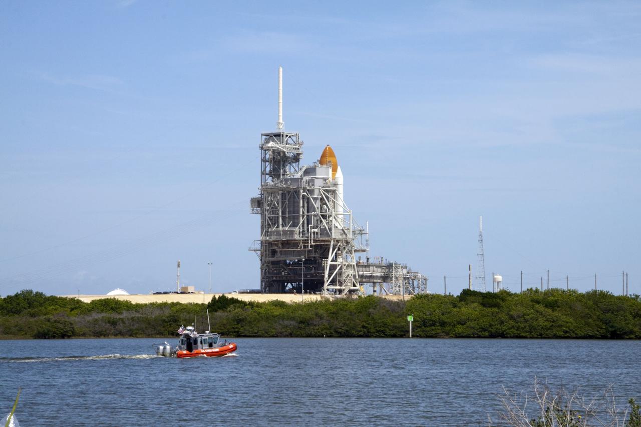 CAPE CANAVERAL, Fla. -- A Coast Guard skiff keeps watch on the waters surrounding space shuttle Atlantis on its seaside launch pad at NASA's Kennedy Space Center in Florida before the shuttle's lift off on the STS-135 mission.          Atlantis and its crew of four; Commander Chris Ferguson, Pilot Doug Hurley, Mission Specialists Sandy Magnus and Rex Walheim are scheduled to lift off at 11:26 a.m. EDT on July 8 to deliver the Raffaello multi-purpose logistics module packed with supplies and spare parts for the International Space Station. Atlantis also will fly the Robotic Refueling Mission experiment that will investigate the potential for robotically refueling existing satellites in orbit. In addition, Atlantis will return with a failed ammonia pump module to help NASA better understand the failure mechanism and improve pump designs for future systems. STS-135 is the 33rd flight of Atlantis, the 37th shuttle mission to the space station, and the 135th and final mission of NASA's Space Shuttle Program. For more information, visit www.nasa.gov/mission_pages/shuttle/shuttlemissions/sts135/index.html. Photo credit: Ken Thornsley