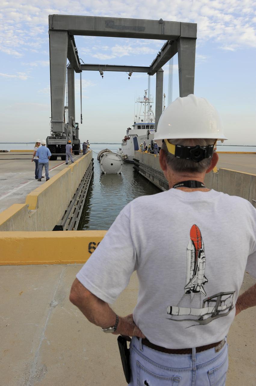 CAPE CANAVERAL, Fla. – Workers watch as Liberty Star, one of NASA’s solid rocket booster retrieval ships, tows a spent booster from space shuttle Atlantis’ final launch, to Port Canaveral in Florida. The shuttle’s two solid rocket booster casings and associated flight hardware are recovered in the Atlantic Ocean after every launch by Freedom Star and Liberty Star. The boosters impact the Atlantic about seven minutes after liftoff, and the retrieval ships are stationed about 10 miles from the impact area at the time of splashdown.    After the spent segments are processed, they will be transported to Utah, where they will be deserviced and stored, if needed. Atlantis began its final flight, STS-135, at 11:29 a.m. EDT on July 8 to deliver the Raffaello multi-purpose logistics module packed with supplies and spare parts to the International Space Station. Photo credit: NASA/Kim Shiflett