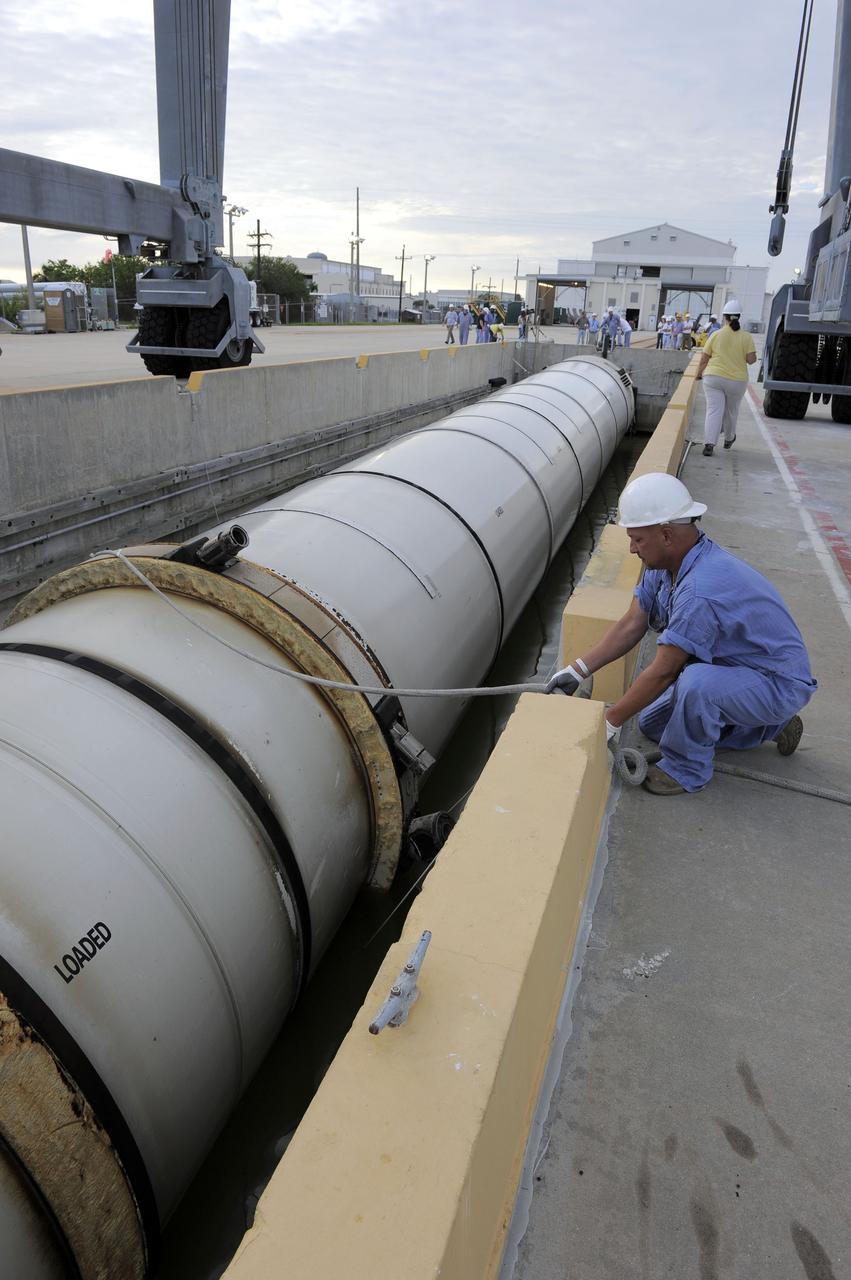 CAPE CANAVERAL, Fla. – A worker secures one of two solid rocket boosters to a mooring at Port Canaveral in Florida.  Liberty Star, one of NASA’s two booster retrieval ships, towed the spent booster from space shuttle Atlantis’ final launch to the port. The shuttle’s two solid rocket booster casings and associated flight hardware are recovered in the Atlantic Ocean after every launch by Freedom Star and Liberty Star. The boosters impact the Atlantic about seven minutes after liftoff, and the retrieval ships are stationed about 10 miles from the impact area at the time of splashdown.    After the spent segments are processed, they will be transported to Utah, where they will be deserviced and stored, if needed. Atlantis began its final flight, STS-135, at 11:29 a.m. EDT on July 8 to deliver the Raffaello multi-purpose logistics module packed with supplies and spare parts to the International Space Station. Photo credit: NASA/Kim Shiflett