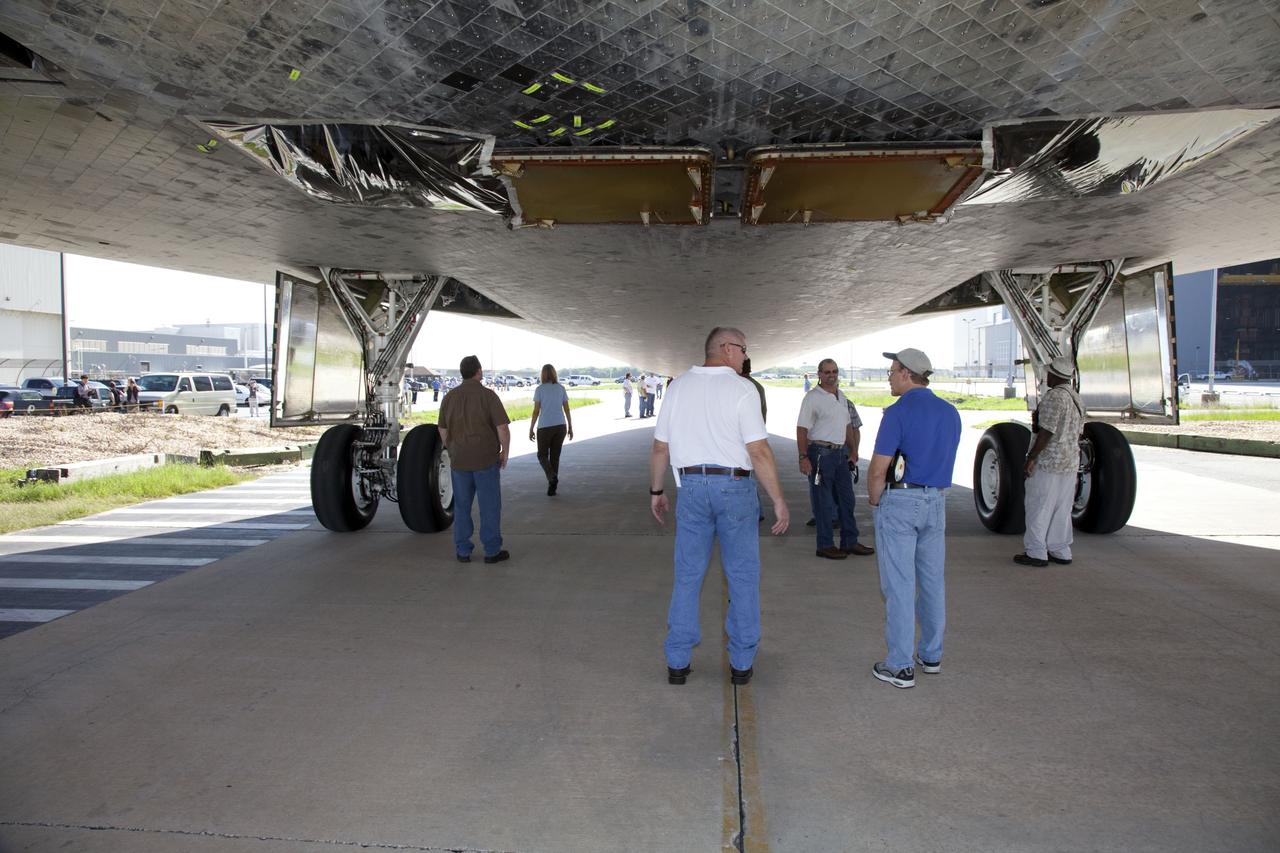 CAPE CANAVERAL, Fla. -- At NASA's Kennedy Space Center in Florida, workers "spotting" for space shuttle Discovery as it rolls from Orbiter Processing Facility-2, or OPF-2, to the Vehicle Assembly Building, or VAB, take refuge from the sun beneath the shuttle. Discovery will be stored inside the VAB for approximately one month while shuttle Atlantis undergoes processing in OPF-2 following its final mission, STS-135. Discovery flew its 39th and final mission, STS-133, in February and March 2011, and currently is being prepared for public display at the Smithsonian's National Air and Space Museum Steven F. Udvar-Hazy Center in Virginia. For more information about Discovery's Transition and Retirement, visit www.nasa.gov/mission_pages/shuttle/launch/discovery_rss_collection_archive_1.html. Photo credit: NASA/Frankie Martin