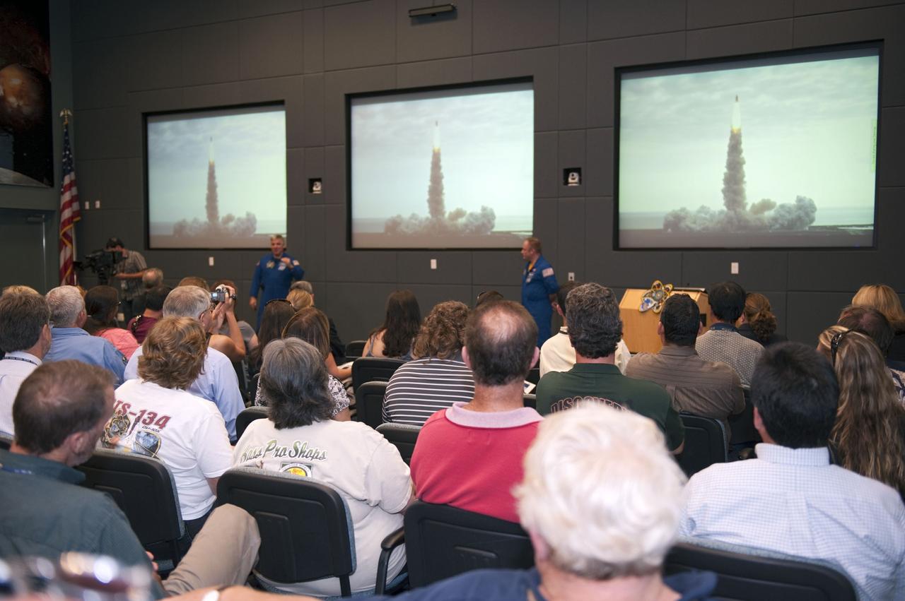 CAPE CANAVERAL, Fla. - STS-134 Pilot Gregory H. Johnson, left, and Mission Specialist Michael Fincke speak to employees at NASA's Kennedy Space Center in Florida during a video presentation, part of a crew return event.     Commander Mark Kelly, Johnson and Mission Specialists Fincke, Greg Chamitoff, Andrew Feustel and European Space Agency astronaut Roberto Vittori lifted off May 16, 2011, aboard space shuttle Endeavour. During the nearly 16-day STS-134 mission, Endeavour delivered to the International Space Station the Alpha Magnetic Spectrometer (AMS) and spare parts, including two S-band communications antennas, a high-pressure gas tank and additional spare parts for Dextre. This was the 36th shuttle mission to the station and Endeavour's 25th and final flight.  For more information, visit www.nasa.gov/mission_pages/shuttle/shuttlemissions/sts134/main/index.html.  Photo credit: NASA/Kim Shiflett