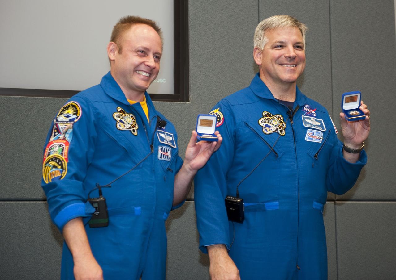 CAPE CANAVERAL, Fla. - During a crew return event at NASA's Kennedy Space Center in Florida, STS-134 Mission Specialist Michael Fincke, left, and Pilot Gregory H. Johnson display commemorative coins given to them by Center Director Bob Cabana.    Commander Mark Kelly, Johnson and Mission Specialists Fincke, Greg Chamitoff, Andrew Feustel and European Space Agency astronaut Roberto Vittori lifted off May 16, 2011, aboard space shuttle Endeavour. During the nearly 16-day STS-134 mission, Endeavour delivered to the International Space Station the Alpha Magnetic Spectrometer (AMS) and spare parts, including two S-band communications antennas, a high-pressure gas tank and additional spare parts for Dextre. This was the 36th shuttle mission to the station and Endeavour's 25th and final flight.  For more information, visit www.nasa.gov/mission_pages/shuttle/shuttlemissions/sts134/main/index.html.  Photo credit: NASA/Kim Shiflett