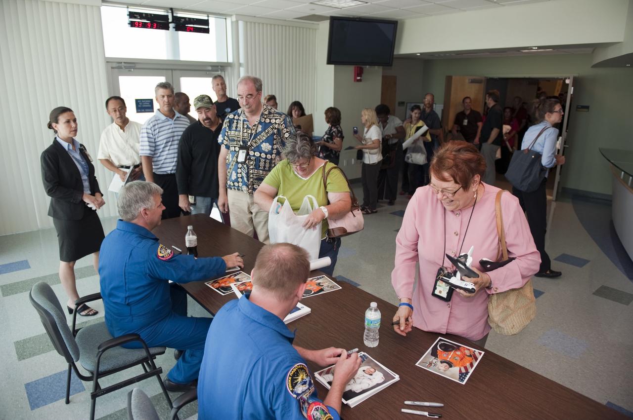 CAPE CANAVERAL, Fla. - Employees line up to visit with STS-134 Pilot Gregory H. Johnson, left, and Mission Specialist Michael Fincke following a crew return event at NASA's Kennedy Space Center in Florida.      Commander Mark Kelly, Johnson and Mission Specialists Fincke, Greg Chamitoff, Andrew Feustel and European Space Agency astronaut Roberto Vittori lifted off May 16, 2011, aboard space shuttle Endeavour. During the nearly 16-day STS-134 mission, Endeavour delivered to the International Space Station the Alpha Magnetic Spectrometer (AMS) and spare parts, including two S-band communications antennas, a high-pressure gas tank and additional spare parts for Dextre. This was the 36th shuttle mission to the station and Endeavour's 25th and final flight.  For more information, visit www.nasa.gov/mission_pages/shuttle/shuttlemissions/sts134/main/index.html.  Photo credit: NASA/Kim Shiflett