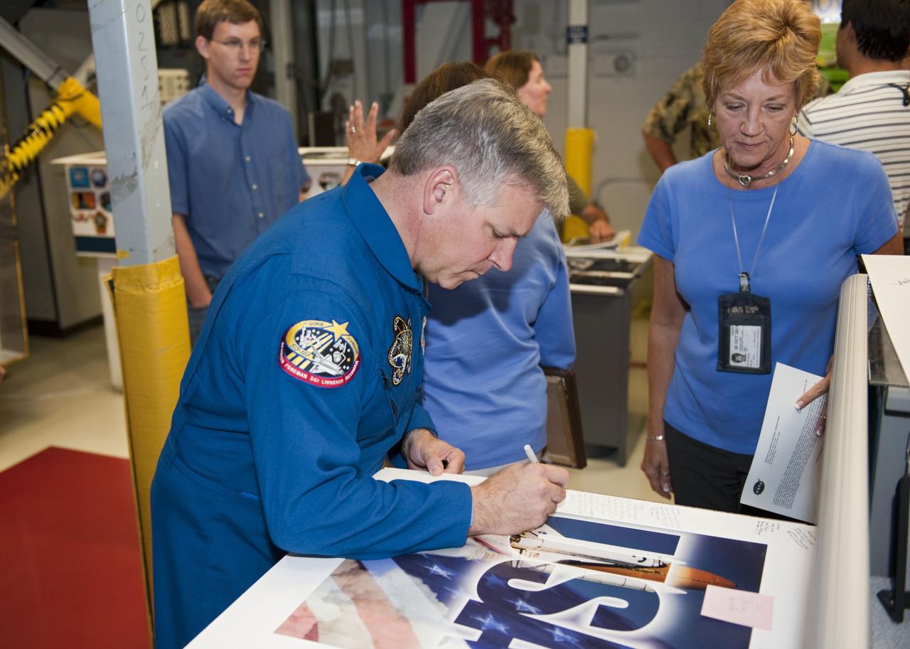 CAPE CANAVERAL, Fla. - STS-134 Pilot Gregory H. Johnson is joined by several employees as he signs a poster inside Orbiter Processing Facility-1 at NASA's Kennedy Space Center in Florida. Also attending the crew return event was STS-134 Mission Specialist Michael Fincke. Commander Mark Kelly, Johnson and Mission Specialists Fincke, Greg Chamitoff, Andrew Feustel and European Space Agency astronaut Roberto Vittori lifted off May 16, 2011 aboard space shuttle Endeavour. During the nearly 16-day STS-134 mission, Endeavour delivered to the International Space Station the Alpha Magnetic Spectrometer (AMS) and spare parts, including two S-band communications antennas, a high-pressure gas tank and additional spare parts for Dextre. This was the 36th shuttle mission to the station and Endeavour's 25th and final flight. For more information, visit www.nasa.gov/mission_pages/shuttle/shuttlemissions/sts134/main/index.html. Photo credit: NASA/Kim Shiflett