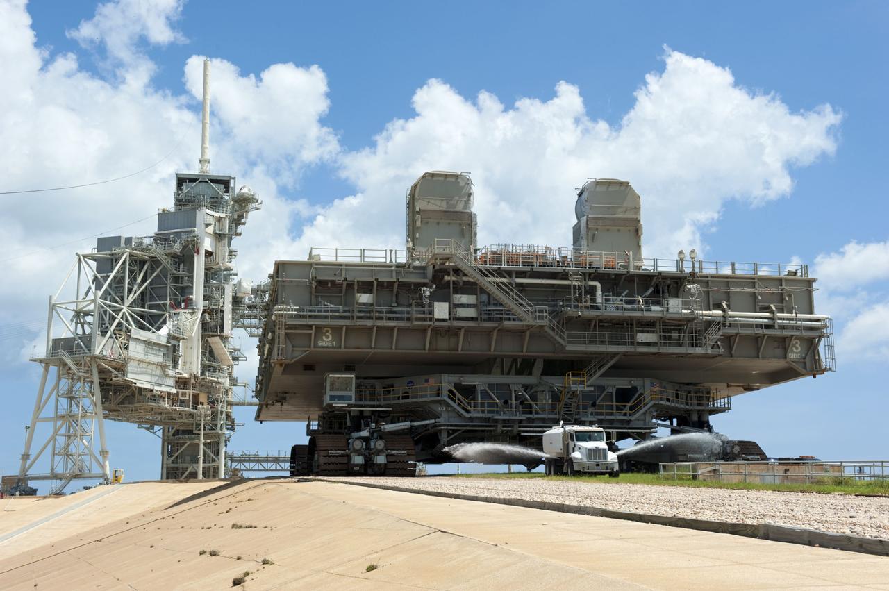 CAPE CANAVERAL, Fla. -- At NASA's Kennedy Space Center in Florida, Mobile Launcher Platform-3 (MLP), which supported space shuttle Atlantis for its final flight to the International Space Station on the STS-135 mission, is taking its last journey from Launch Pad 39A to the Vehicle Assembly Building (VAB). A massive crawler-transporter positioned under the MLP -- the last mobile launcher platform to launch a shuttle, begins the trek back to the VAB. A water truck leads the way spraying water on the dry crawlerway to reduce dust particles in the air.                     For more than 40 years, the MLPs have traveled between the massive VAB to both launch pads at Launch Complex 39, and then returned to the VAB for future use. MLP-3 was first used to launch Columbia on the STS-32 mission on Jan. 9, 1990. Photo credit: NASA/Kim Shiflett