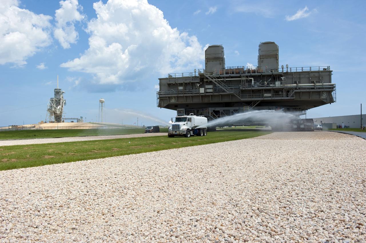 CAPE CANAVERAL, Fla. -- At NASA's Kennedy Space Center in Florida, Mobile Launcher Platform-3 (MLP), which supported space shuttle Atlantis for its final flight to the International Space Station on the STS-135 mission, is taking its last journey from Launch Pad 39A to the Vehicle Assembly Building (VAB). A massive crawler-transporter positioned under the MLP -- the last mobile launcher platform to launch a shuttle, begins the trek back to the VAB. A water truck leads the way spraying water on the dry crawlerway to reduce dust particles in the air.                     For more than 40 years, the MLPs have traveled between the massive VAB to both launch pads at Launch Complex 39, and then returned to the VAB for future use. MLP-3 was first used to launch Columbia on the STS-32 mission on Jan. 9, 1990. Photo credit: NASA/Kim Shiflett