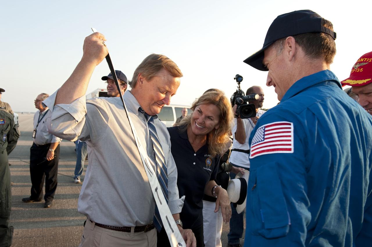 CAPE CANAVERAL, Fla. -- Shuttle Launch Director Mike Leinbach proudly displays a space shuttle Atlantis banner for STS-135 Commander Chris Ferguson, front right, and Pilot Doug Hurley. Four astronauts brought Atlantis home to the Shuttle Landing Facility's Runway 15 at NASA's Kennedy Space Center in Florida at 5:57 a.m. EDT bringing a close NASA's Space Shuttle Program. Atlantis' final return from space completed a 13-day, 5.2-million-mile journey to the International Space Station.                  STS-135 delivered spare parts, equipment and supplies in the Raffaello multi-purpose logistics module that will sustain station operations for the next year. STS-135 was the 33rd and final flight for Atlantis, which has spent 307 days in space, orbited Earth 4,848 times and traveled 125,935,769 miles. For more information visit, www.nasa.gov/mission_pages/shuttle/shuttlemissions/sts135/index.html. Photo credit: NASA/Kim Shiflett