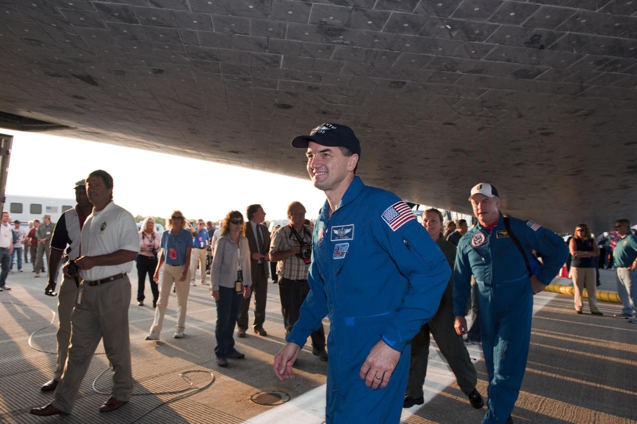 CAPE CANAVERAL, Fla. -- The STS-135 Mission Specialist Rex Walheim, front center, takes a stroll underneath space shuttle Atlantis following a successful mission to the International Space Station. Four astronauts brought Atlantis home to the Shuttle Landing Facility's Runway 15 at NASA's Kennedy Space Center in Florida at 5:57 a.m. EDT bringing a close NASA's Space Shuttle Program. Atlantis' final return from space completed a 13-day, 5.2-million-mile journey to the International Space Station.                  STS-135 delivered spare parts, equipment and supplies in the Raffaello multi-purpose logistics module that will sustain station operations for the next year. STS-135 was the 33rd and final flight for Atlantis, which has spent 307 days in space, orbited Earth 4,848 times and traveled 125,935,769 miles. For more information visit, www.nasa.gov/mission_pages/shuttle/shuttlemissions/sts135/index.html. Photo credit: NASA/Kim Shiflett