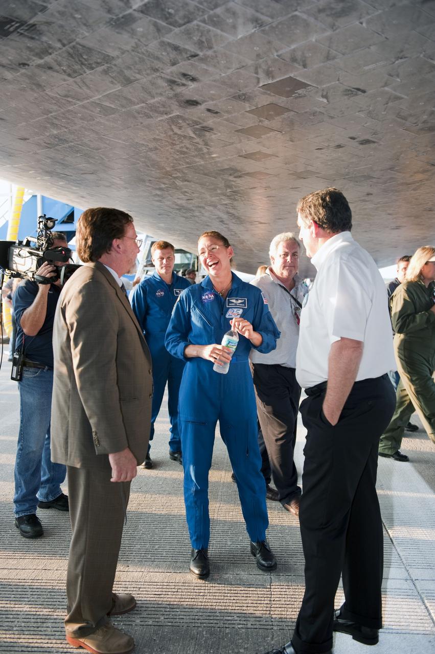 CAPE CANAVERAL, Fla. -- The STS-135 Mission Specialist Sandy Magnus, center, chats underneath space shuttle Atlantis following a successful mission to the International Space Station. Four astronauts brought Atlantis home to the Shuttle Landing Facility's Runway 15 at NASA's Kennedy Space Center in Florida at 5:57 a.m. EDT bringing a close NASA's Space Shuttle Program. Atlantis' final return from space completed a 13-day, 5.2-million-mile journey to the International Space Station.                STS-135 delivered spare parts, equipment and supplies in the Raffaello multi-purpose logistics module that will sustain station operations for the next year. STS-135 was the 33rd and final flight for Atlantis, which has spent 307 days in space, orbited Earth 4,848 times and traveled 125,935,769 miles. For more information visit, www.nasa.gov/mission_pages/shuttle/shuttlemissions/sts135/index.html. Photo credit: NASA/Kim Shiflett