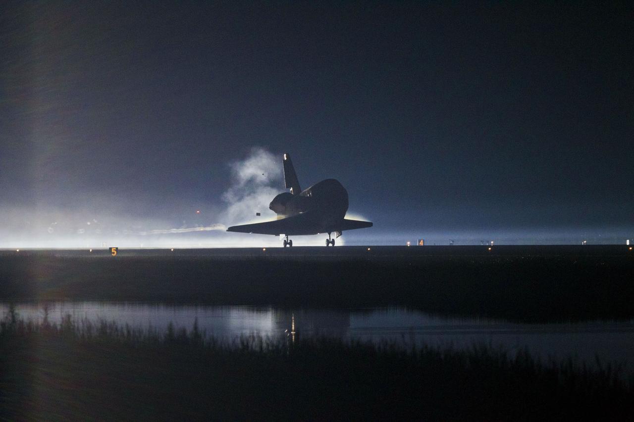 CAPE CANAVERAL, Fla. -- The cloud forming behind space shuttle Atlantis foretells the deployment of the shuttle's drag chute as it lands on Runway 15 at the Shuttle Landing Facility at NASA's Kennedy Space Center in Florida. Securing the space shuttle fleet's place in history, Atlantis marked the 26th nighttime landing of NASA's Space Shuttle Program and the 78th landing at Kennedy. Main gear touchdown was at 5:57:00 a.m. EDT, followed by nose gear touchdown at 5:57:20 a.m., and wheelstop at 5:57:54 a.m. On board are STS-135 Commander Chris Ferguson, Pilot Doug Hurley, and Mission Specialists Sandra Magnus and Rex Walheim.    On the 37th shuttle mission to the International Space Station, STS-135 delivered the Raffaello multi-purpose logistics module filled with more than 9,400 pounds of spare parts, equipment and supplies that will sustain station operations for the next year. STS-135 was the 33rd and final flight for Atlantis, which has spent 307 days in space, orbited Earth 4,848 times and traveled 125,935,769 miles. STS-135 also was the final mission of the Space Shuttle Program.  For more information, visit www.nasa.gov/mission_pages/shuttle/shuttlemissions/sts135/index.html. Photo credit: NASA/Kenny Allen