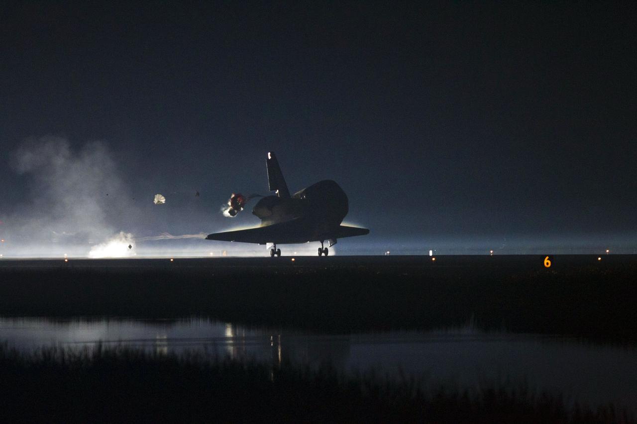 CAPE CANAVERAL, Fla. -- Space shuttle Atlantis' pilot chute deploys, pulling the shuttle's drag chute into view, as the shuttle lands on Runway 15 at the Shuttle Landing Facility at NASA's Kennedy Space Center in Florida. Securing the space shuttle fleet's place in history, Atlantis marked the 26th nighttime landing of NASA's Space Shuttle Program and the 78th landing at Kennedy. Main gear touchdown was at 5:57:00 a.m. EDT, followed by nose gear touchdown at 5:57:20 a.m., and wheelstop at 5:57:54 a.m. On board are STS-135 Commander Chris Ferguson, Pilot Doug Hurley, and Mission Specialists Sandra Magnus and Rex Walheim.    On the 37th shuttle mission to the International Space Station, STS-135 delivered the Raffaello multi-purpose logistics module filled with more than 9,400 pounds of spare parts, equipment and supplies that will sustain station operations for the next year. STS-135 was the 33rd and final flight for Atlantis, which has spent 307 days in space, orbited Earth 4,848 times and traveled 125,935,769 miles. STS-135 also was the final mission of the Space Shuttle Program.  For more information, visit www.nasa.gov/mission_pages/shuttle/shuttlemissions/sts135/index.html. Photo credit: NASA/Kenny Allen