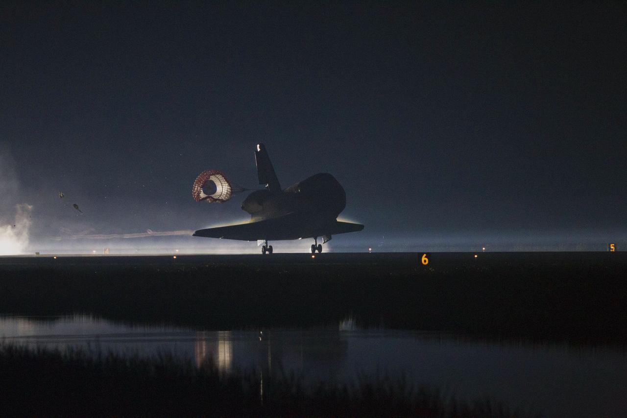 CAPE CANAVERAL, Fla. -- Space shuttle Atlantis' drag chute deploys to slow the shuttle as it lands on Runway 15 at the Shuttle Landing Facility at NASA's Kennedy Space Center in Florida. Securing the space shuttle fleet's place in history, Atlantis marked the 26th nighttime landing of NASA's Space Shuttle Program and the 78th landing at Kennedy. Main gear touchdown was at 5:57:00 a.m. EDT, followed by nose gear touchdown at 5:57:20 a.m., and wheelstop at 5:57:54 a.m. On board are STS-135 Commander Chris Ferguson, Pilot Doug Hurley, and Mission Specialists Sandra Magnus and Rex Walheim.    On the 37th shuttle mission to the International Space Station, STS-135 delivered the Raffaello multi-purpose logistics module filled with more than 9,400 pounds of spare parts, equipment and supplies that will sustain station operations for the next year. STS-135 was the 33rd and final flight for Atlantis, which has spent 307 days in space, orbited Earth 4,848 times and traveled 125,935,769 miles. STS-135 also was the final mission of the Space Shuttle Program.  For more information, visit www.nasa.gov/mission_pages/shuttle/shuttlemissions/sts135/index.html. Photo credit: NASA/Kenny Allen