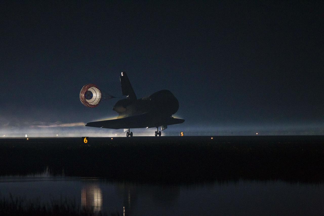 CAPE CANAVERAL, Fla. -- Space shuttle Atlantis, trailed by its drag chute, lands on Runway 15 at the Shuttle Landing Facility at NASA's Kennedy Space Center in Florida. Securing the space shuttle fleet's place in history, Atlantis marked the 26th nighttime landing of NASA's Space Shuttle Program and the 78th landing at Kennedy. Main gear touchdown was at 5:57:00 a.m. EDT, followed by nose gear touchdown at 5:57:20 a.m., and wheelstop at 5:57:54 a.m. On board are STS-135 Commander Chris Ferguson, Pilot Doug Hurley, and Mission Specialists Sandra Magnus and Rex Walheim.    On the 37th shuttle mission to the International Space Station, STS-135 delivered the Raffaello multi-purpose logistics module filled with more than 9,400 pounds of spare parts, equipment and supplies that will sustain station operations for the next year. STS-135 was the 33rd and final flight for Atlantis, which has spent 307 days in space, orbited Earth 4,848 times and traveled 125,935,769 miles. STS-135 also was the final mission of the Space Shuttle Program.  For more information, visit www.nasa.gov/mission_pages/shuttle/shuttlemissions/sts135/index.html. Photo credit: NASA/Kenny Allen