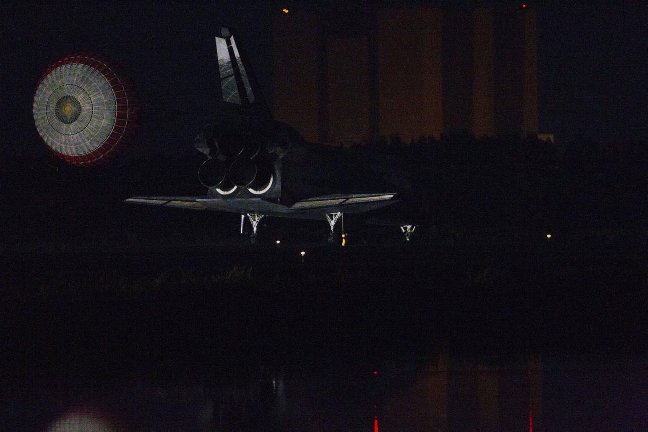 CAPE CANAVERAL, Fla. -- At the Shuttle Landing Facility at NASA's Kennedy Space Center in Florida, the drag chute trailing space shuttle Atlantis slows the near-invisible shuttle for landing on Runway 15 one final time.  In the background is the Vehicle Assembly Building, still engulfed in darkness.  Securing the space shuttle fleet's place in history, Atlantis marked the 26th nighttime landing of NASA's Space Shuttle Program and the 78th landing at Kennedy. Main gear touchdown was at 5:57:00 a.m. EDT, followed by nose gear touchdown at 5:57:20 a.m., and wheelstop at 5:57:54 a.m. On board are STS-135 Commander Chris Ferguson, Pilot Doug Hurley, and Mission Specialists Sandra Magnus and Rex Walheim.    On the 37th shuttle mission to the International Space Station, STS-135 delivered the Raffaello multi-purpose logistics module filled with more than 9,400 pounds of spare parts, equipment and supplies that will sustain station operations for the next year. STS-135 was the 33rd and final flight for Atlantis, which has spent 307 days in space, orbited Earth 4,848 times and traveled 125,935,769 miles. STS-135 also was the final mission of the Space Shuttle Program.  For more information, visit www.nasa.gov/mission_pages/shuttle/shuttlemissions/sts135/index.html. Photo credit: NASA/Kenny Allen