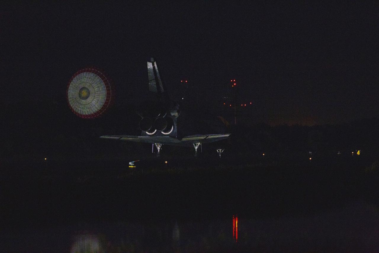CAPE CANAVERAL, Fla. -- Space shuttle Atlantis, trailed by its drag chute, rolls to a stop on Runway 15 at the Shuttle Landing Facility at NASA's Kennedy Space Center in Florida. Securing the space shuttle fleet's place in history, Atlantis marked the 26th nighttime landing of NASA's Space Shuttle Program and the 78th landing at Kennedy. Main gear touchdown was at 5:57:00 a.m. EDT, followed by nose gear touchdown at 5:57:20 a.m., and wheelstop at 5:57:54 a.m. On board are STS-135 Commander Chris Ferguson, Pilot Doug Hurley, and Mission Specialists Sandra Magnus and Rex Walheim.    On the 37th shuttle mission to the International Space Station, STS-135 delivered the Raffaello multi-purpose logistics module filled with more than 9,400 pounds of spare parts, equipment and supplies that will sustain station operations for the next year. STS-135 was the 33rd and final flight for Atlantis, which has spent 307 days in space, orbited Earth 4,848 times and traveled 125,935,769 miles. STS-135 also was the final mission of the Space Shuttle Program.  For more information, visit www.nasa.gov/mission_pages/shuttle/shuttlemissions/sts135/index.html. Photo credit: NASA/Kenny Allen