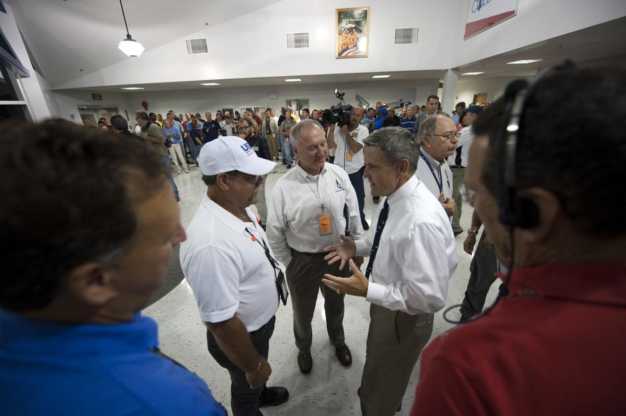 CAPE CANAVERAL, Fla. -- In the Flight Vehicle Support Building at NASA Kennedy Space Center's Shuttle Landing Facility (SLF), Kennedy Center Director Bob Cabana speaks with Closeout Crew lead Travis Thompson (left), and STS-135 Assistant Launch Director Pete Nickolenko during a prelanding convoy meeting. A Convoy Command Center vehicle will be positioned near shuttle Atlantis on the SLF. The command vehicle is equipped to control critical communications between the crew still aboard Atlantis and the Launch Control Center. The team will monitor the health of the orbiter systems and direct convoy operations made up of about 40 vehicles, including 25 specially designed vehicles to assist the crew in leaving the shuttle, and prepare the vehicle for towing from the SLF to its processing hangar.    Securing the space shuttle fleet's place in history, Atlantis will mark the 26th nighttime landing of NASA's Space Shuttle Program and the 78th landing at Kennedy. Atlantis and its crew delivered to the International Space Station the Raffaello multi-purpose logistics module packed with more than 9,400 pounds of spare parts, equipment and supplies that will sustain station operations for the next year. STS-135 is the 33rd and final flight for Atlantis and final mission of the Space Shuttle Program. For more information, visit www.nasa.gov/mission_pages/shuttle/shuttlemissions/sts135/index.html. Photo credit: NASA/Kim Shiflett