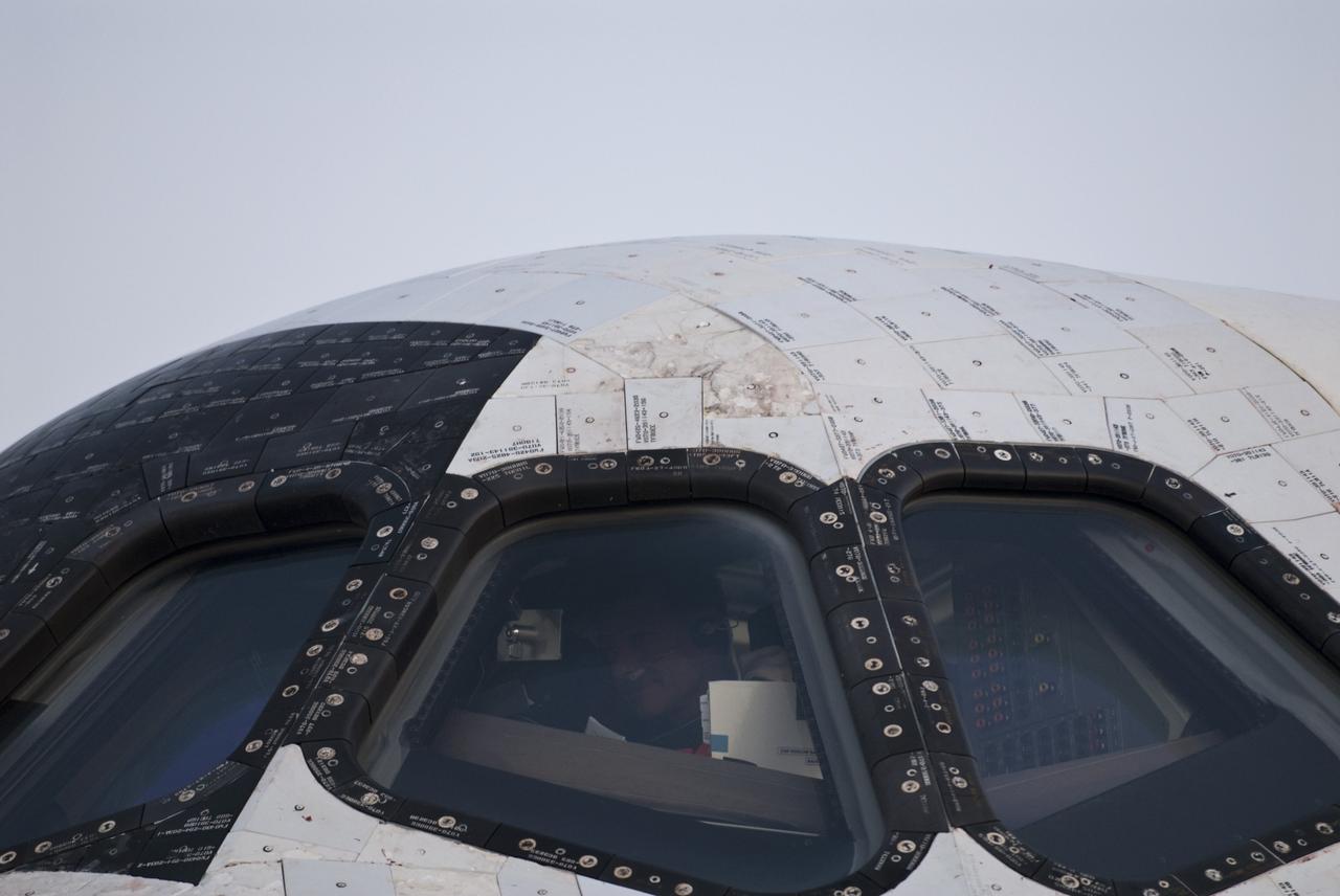 CAPE CANAVERAL, Fla. -- A towback technician is seen through the cockpit windows of space shuttle Atlantis as he safes the vehicle on the Shuttle Landing Facility's  Runway 15 at NASA's Kennedy Space Center in Florida. Atlantis' final landing was the 26th nighttime landing of NASA's Space Shuttle Program and the 78th landing at Kennedy. Main gear touchdown was at 5:57:00 a.m. EDT, followed by nose gear touchdown at 5:57:20 a.m., and wheelstop at 5:57:54 a.m. On board were STS-135 Commander Chris Ferguson, Pilot Doug Hurley, and Mission Specialists Sandra Magnus and Rex Walheim.    On the 37th shuttle mission to the International Space Station, STS-135 delivered the Raffaello multi-purpose logistics module filled with more than 9,400 pounds of spare parts, equipment and supplies that will sustain station operations for the next year. STS-135 was the 33rd and final flight for Atlantis, which has spent 307 days in space, orbited Earth 4,848 times and traveled 125,935,769 miles, and also the final mission of the Space Shuttle Program.  For more information, visit www.nasa.gov/mission_pages/shuttle/shuttlemissions/sts135/index.html. Photo credit: NASA/Kim Shiflett