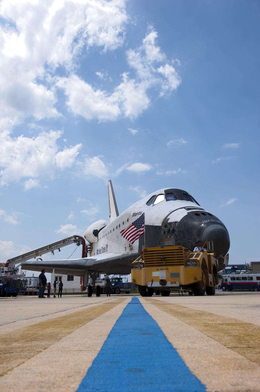 CAPE CANAVERAL, Fla. -- A "towback" vehicle slowly pulls space shuttle Atlantis toward Orbiter Processing Facility-2 at NASA's Kennedy Space Center in Florida. A purge unit that pumps conditioned air into a shuttle after landing is connected to Atlantis' aft end. Once inside the processing facility, Atlantis will be prepared for future public display at Kennedy's Visitor Complex.    Atlantis' final return from space at 5:57 a.m. EDT concluded the STS-135 mission, secured the space shuttle fleet's place in history and brought a close to America's Space Shuttle Program. Main gear touchdown was at 5:57:00 a.m. EDT, followed by nose gear touchdown at 5:57:20 a.m., and wheelstop at 5:57:54 a.m. On board were STS-135 Commander Chris Ferguson, Pilot Doug Hurley, and Mission Specialists Sandra Magnus and Rex Walheim.  On the 37th shuttle mission to the International Space Station, STS-135 delivered the Raffaello multi-purpose logistics module filled with more than 9,400 pounds of spare parts, equipment and supplies that will sustain station operations for the next year. STS-135 was the 33rd and final flight for Atlantis, which has spent 307 days in space, orbited Earth 4,848 times and traveled 125,935,769 miles, and also the final mission of the Space Shuttle Program.  For more information, visit www.nasa.gov/mission_pages/shuttle/shuttlemissions/sts135/index.html. Photo credit: NASA/Kim Shiflett