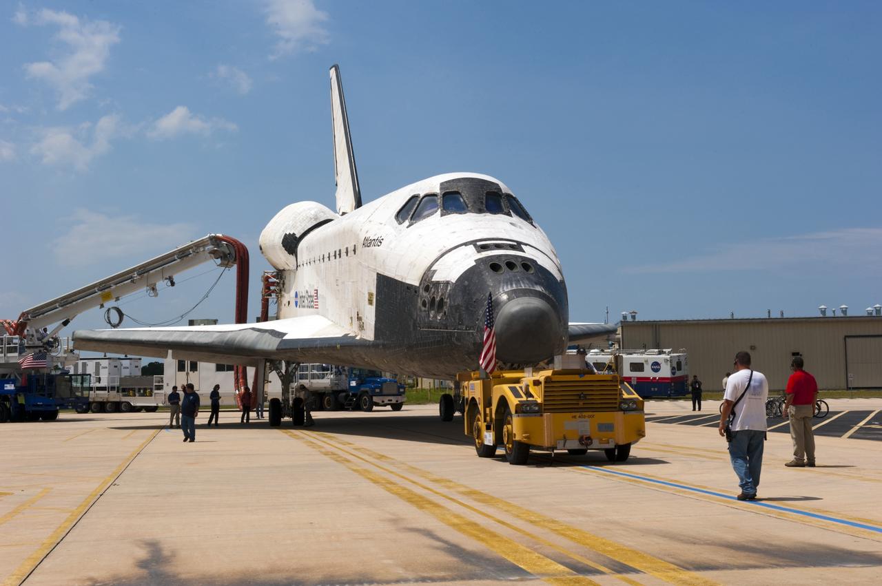 CAPE CANAVERAL, Fla. -- A "towback" vehicle slowly pulls space shuttle Atlantis toward Orbiter Processing Facility-2 at NASA's Kennedy Space Center in Florida. A purge unit that pumps conditioned air into a shuttle after landing is connected to Atlantis' aft end. Once inside the processing facility, Atlantis will be prepared for future public display at Kennedy's Visitor Complex.    Atlantis' final return from space at 5:57 a.m. EDT concluded the STS-135 mission, secured the space shuttle fleet's place in history and brought a close to America's Space Shuttle Program. Main gear touchdown was at 5:57:00 a.m. EDT, followed by nose gear touchdown at 5:57:20 a.m., and wheelstop at 5:57:54 a.m. On board were STS-135 Commander Chris Ferguson, Pilot Doug Hurley, and Mission Specialists Sandra Magnus and Rex Walheim.  On the 37th shuttle mission to the International Space Station, STS-135 delivered the Raffaello multi-purpose logistics module filled with more than 9,400 pounds of spare parts, equipment and supplies that will sustain station operations for the next year. STS-135 was the 33rd and final flight for Atlantis, which has spent 307 days in space, orbited Earth 4,848 times and traveled 125,935,769 miles, and also the final mission of the Space Shuttle Program.  For more information, visit www.nasa.gov/mission_pages/shuttle/shuttlemissions/sts135/index.html. Photo credit: NASA/Kim Shiflett