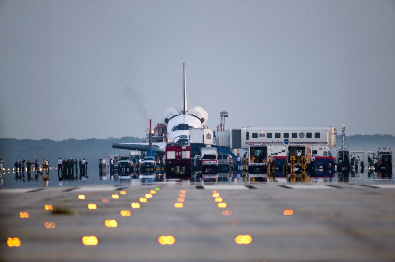 CAPE CANAVERAL, Fla. -- Landing convoy vehicles surround space shuttle Atlantis following its touchdown on Runway 15 at the Shuttle Landing Facility at NASA's Kennedy Space Center in Florida.  The employees assigned to the convoy team prepare to safe the spacecraft before it is towed to Orbiter Processing Facility-2 for decommissioning.  Atlantis marked the 26th nighttime landing of NASA's Space Shuttle Program and the 78th landing at Kennedy. Main gear touchdown was at 5:57:00 a.m. EDT, followed by nose gear touchdown at 5:57:20 a.m., and wheelstop at 5:57:54 a.m. On board are STS-135 Commander Chris Ferguson, Pilot Doug Hurley, and Mission Specialists Sandy Magnus and Rex Walheim.    On the 37th shuttle mission to the International Space Station, STS-135 delivered the Raffaello multi-purpose logistics module filled with more than 9,400 pounds of spare parts, equipment and supplies that will sustain station operations for the next year. STS-135 was the 33rd and final flight for Atlantis, which has spent 307 days in space, orbited Earth 4,848 times and traveled 125,935,769 miles. STS-135 also was the final mission of the Space Shuttle Program.  For more information, visit www.nasa.gov/mission_pages/shuttle/shuttlemissions/sts135/index.html. Photo credit: NASA/Tom Farrar and Tony Gray