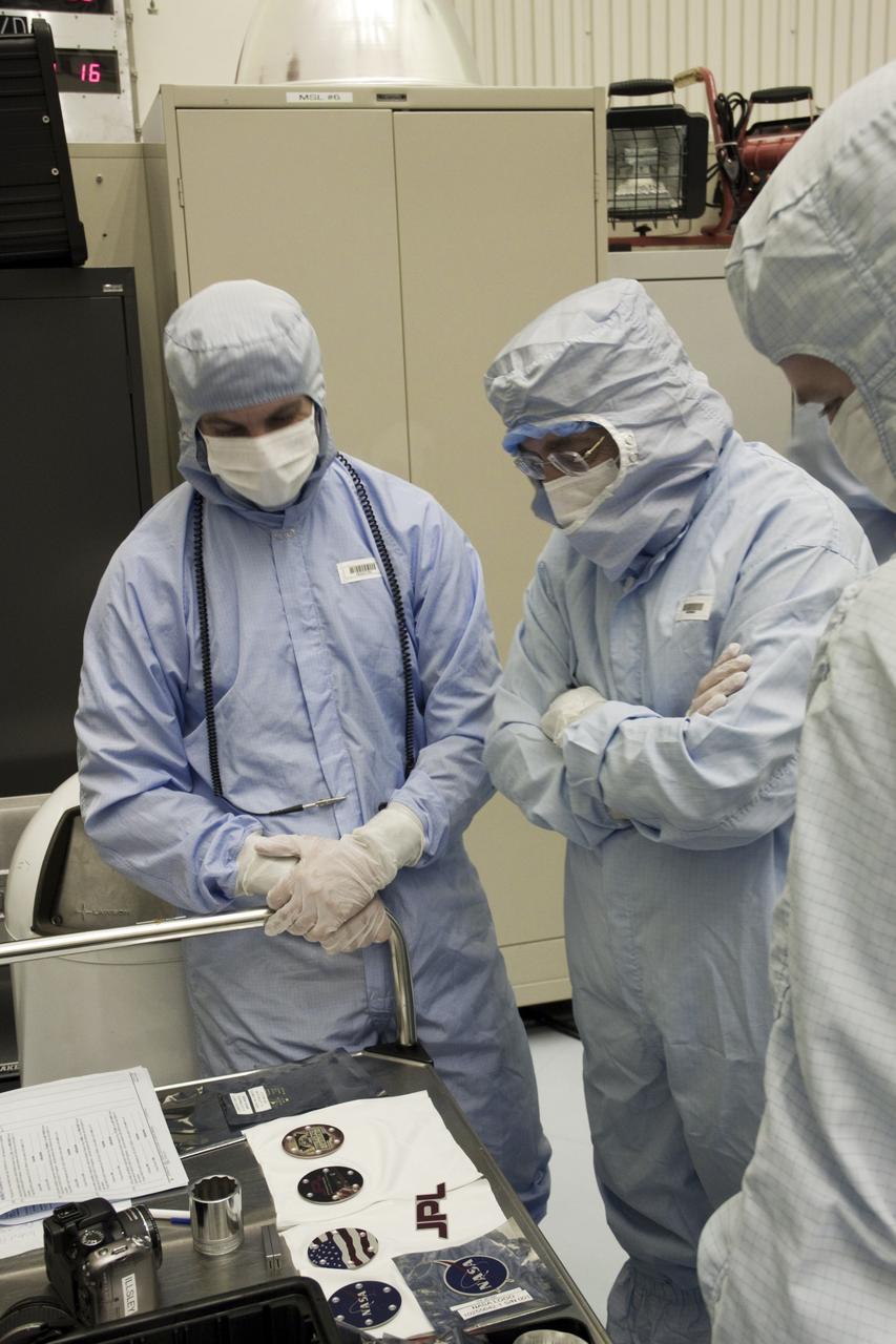 Cape Canaveral, Fla. -- At the Payload Hazardous Servicing Facility at NASA's Kennedy Space Center in Florida, Dr. Charles Elachi, Director of Advanced Planning at NASA's Jet Propulsion Laboratory (center), is shown the medallions that will be affixed to NASA's Mars Science Laboratory (MSL) rover known as Curiosity during processing for flight. A United Launch Alliance Atlas V-541 configuration will be used to loft MSL into space. Curiosity’s 10 science instruments are designed to search for evidence on whether Mars has had environments favorable to microbial life, including chemical ingredients for life. The unique rover will use a laser to look inside rocks and release its gasses so that the rover’s spectrometer can analyze and send the data back to Earth. MSL is scheduled to launch from Cape Canaveral Air Force Station in Florida Nov. 25 with a window extending to Dec. 18 and arrival at Mars Aug. 2012. For more information, visit http://www.nasa.gov/msl. Photo credit: NASA/Jim Grossmann