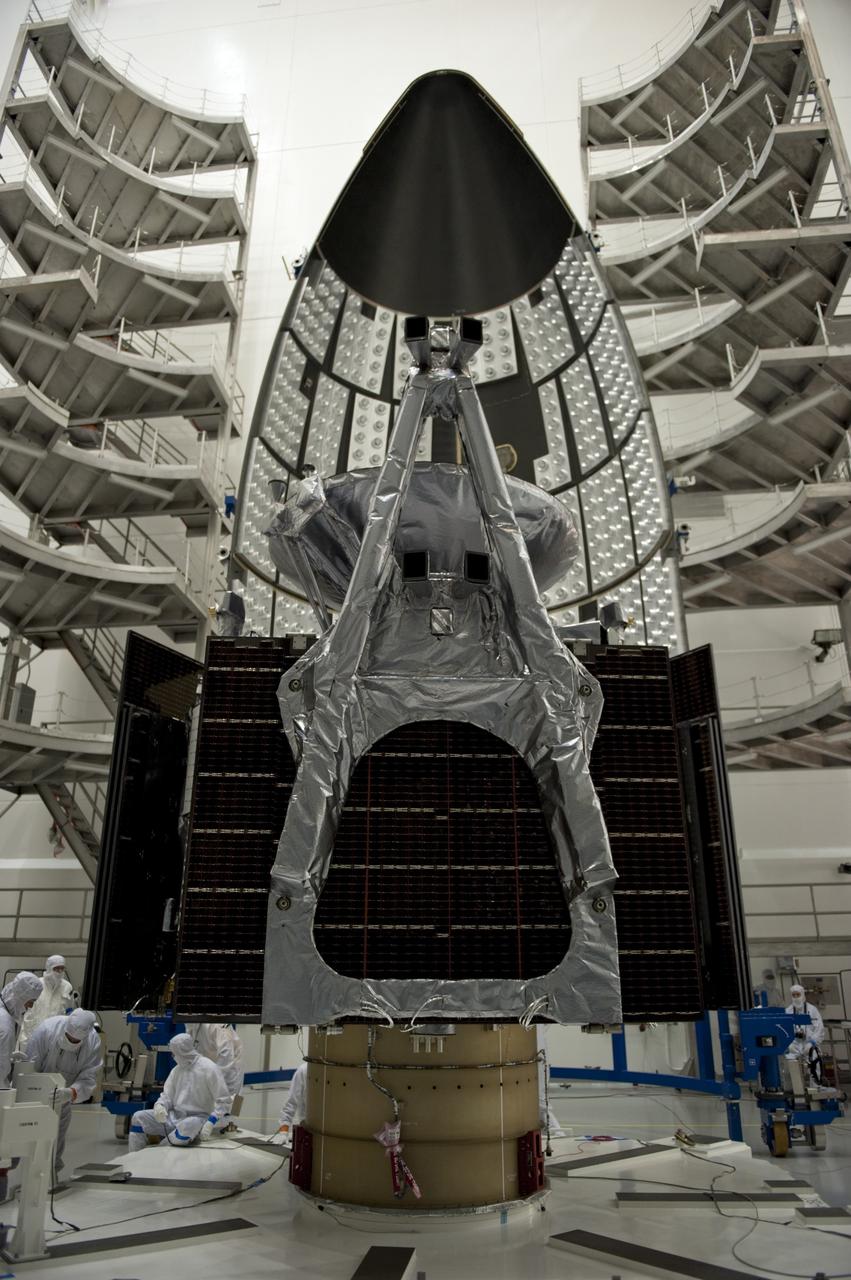CAPE CANAVERAL, Fla. -- In the Astrotech payload processing facility near Kennedy Space Center in Florida, half of the Atlas payload fairing appears to loom above the Juno spacecraft as work to enclose the spacecraft for launch gets under way.    The fairing will protect the spacecraft from the impact of aerodynamic pressure and heating during ascent and will be jettisoned once the spacecraft is outside the Earth's atmosphere. Juno is scheduled to launch aboard a United Launch Alliance Atlas V rocket from Cape Canaveral, Fla., Aug. 5.The solar-powered spacecraft will orbit Jupiter's poles 33 times to find out more about the gas giant's origins, structure, atmosphere and magnetosphere and investigate the existence of a solid planetary core. For more information, visit www.nasa.gov/juno. Photo credit: NASA/Kim Shiflett