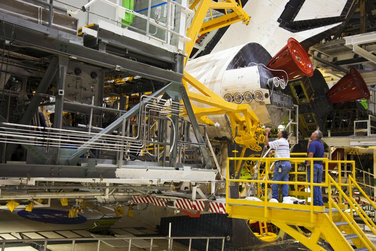 CAPE CANAVERAL, Fla. -- In Orbiter Processing Facility-1 at NASA’s Kennedy Space Center in Florida, workers monitor the progress as an overhead crane is moved into place to begin the process of removing shuttle Endeavour’s left-hand orbital maneuvering system, or OMS, pod. The work is part of Endeavour’s transition and retirement processing. The spacecraft is being prepared for public display at the California Science Center in Los Angeles. Endeavour flew 25 missions, spent 299 days in space, orbited Earth 4,671 times and traveled 122, 883, 151 miles over the course of its 19-year career. Endeavour’s STS-134 and final mission was completed after landing on June 1, 2011. Photo credit: Frank Michaux
