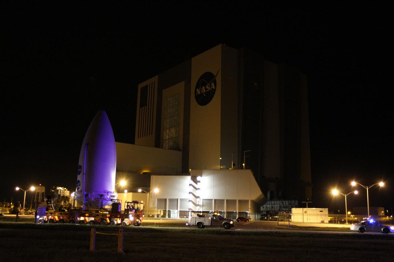 CAPE CANAVERAL, Fla. -- The Juno spacecraft, enclosed in an Atlas payload fairing, rolls past the 525-foot-tall Vehicle Assembly Building in Kennedy Space Center's Launch Complex 39 on its way to Space Launch Complex 41. The spacecraft was prepared for launch in the Astrotech Space Operations' payload processing facility in Titusville, Fla.    The fairing will protect the spacecraft from the impact of aerodynamic pressure and heating during ascent and will be jettisoned once the spacecraft is outside the Earth's atmosphere. Juno is scheduled to launch Aug. 5 aboard a United Launch Alliance Atlas V rocket from Cape Canaveral Air Force Station in Florida. The solar-powered spacecraft will orbit Jupiter's poles 33 times to find out more about the gas giant's origins, structure, atmosphere and magnetosphere and investigate the existence of a solid planetary core. For more information, visit www.nasa.gov/juno. Photo credit: NASA/Cory Huston