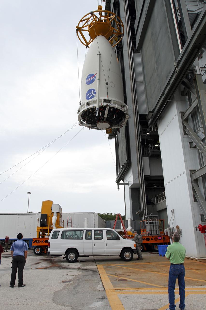 CAPE CANAVERAL, Fla. -- At Space Launch Complex 41, the Juno spacecraft, enclosed in an Atlas payload fairing, appears to hover over its transporter as it is lifted up the side of the Vertical Integration Facility to the top of the Atlas rocket already stacked inside.  The spacecraft was prepared for launch in the Astrotech Space Operations' payload processing facility in Titusville, Fla.    The fairing will protect the spacecraft from the impact of aerodynamic pressure and heating during ascent and will be jettisoned once the spacecraft is outside the Earth's atmosphere. Juno is scheduled to launch Aug. 5 aboard a United Launch Alliance Atlas V rocket from Cape Canaveral Air Force Station in Florida. The solar-powered spacecraft will orbit Jupiter's poles 33 times to find out more about the gas giant's origins, structure, atmosphere and magnetosphere and investigate the existence of a solid planetary core. For more information, visit www.nasa.gov/juno. Photo credit: NASA/Cory Huston