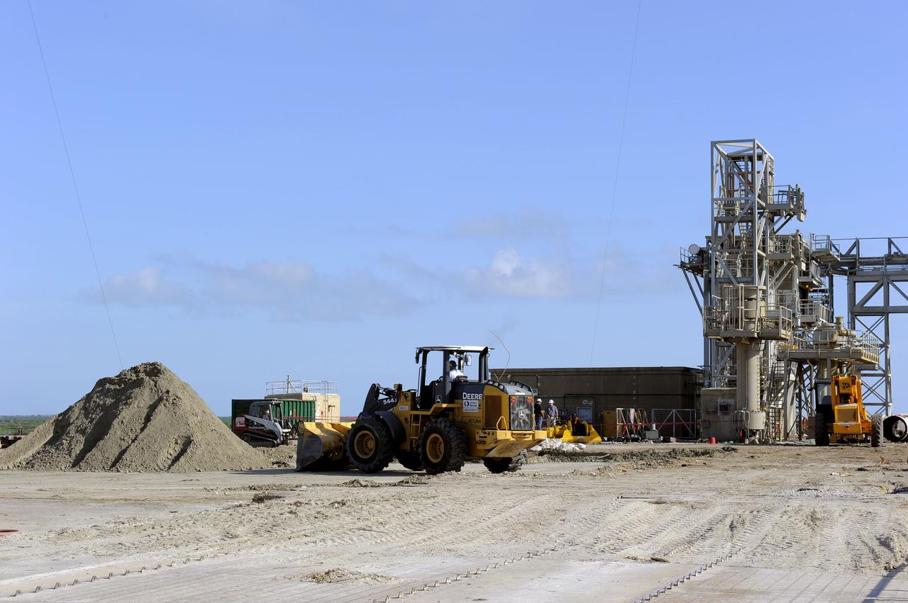 CAPE CANAVERAL, Fla. -- At NASA's Kennedy Space Center in Florida, a bulldozer is enlisted in the cleanup of Launch Pad 39B. Sand, reinforcing steel and large wooden mats were placed over the pad's concrete surfaces during deconstruction to protect them from falling debris. In 2009, the structure at the pad was no longer needed for NASA's Space Shuttle Program, so it is being restructured for future use. The new design will feature a "clean pad" for rockets to come with their own launcher, making it more versatile for a number of rockets and spacecraft. The lightning protection system, consisting of three lightning towers and a wire catenary system, will remain. For information on NASA's future plans, visit http://www.nasa.gov/exploration. Photo credit: NASA/Kim Shiflett