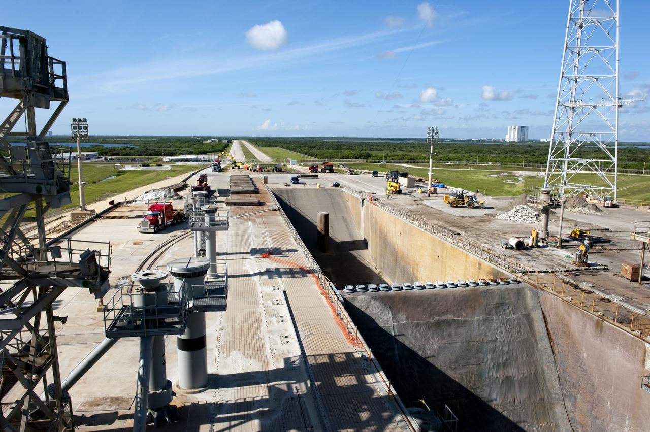 CAPE CANAVERAL, Fla. -- At NASA's Kennedy Space Center in Florida, cleanup of Launch Pad 39B is in progress beside the pad's flame trench. The trench is 450 feet long, 58 feet wide and 42 feet deep with an inner inverted V-shaped steel flame deflector. Sand, reinforcing steel and large wooden mats were placed over the pad's concrete surfaces during deconstruction to protect them from falling debris. In the distance is the 525-foot-tall Vehicle Assembly Building. In 2009, the structure at the pad was no longer needed for NASA's Space Shuttle Program, so it is being restructured for future use. The new design will feature a "clean pad" for rockets to come with their own launcher, making it more versatile for a number of rockets and spacecraft. The lightning protection system, consisting of three lightning towers and a wire catenary system, will remain. For information on NASA's future plans, visit http://www.nasa.gov/exploration. Photo credit: NASA/Kim Shiflett