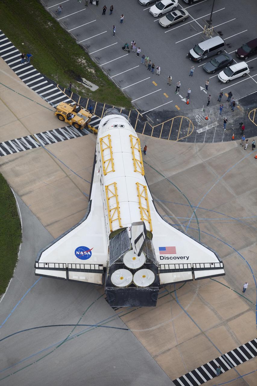 CAPE CANAVERAL, Fla. -- At NASA's Kennedy Space Center in Florida, space shuttle Discovery rolls out of the Vehicle Assembly Building (VAB) past employees and media representatives eager to take a few photographs.  Discovery is switching places with shuttle Endeavour which has been undergoing decommissioning in Orbiter Processing Facility-1 (OPF-1).  Both shuttles will stop briefly outside OPF-3 for a "nose-to-nose" photo opportunity. Discovery then will be rolled into OPF-1 and Endeavour into the VAB.    The image was taken from the top of the VAB.  In OPF-1, Discovery will undergo further preparations for public display at the Smithsonian's National Air and Space Museum Steven F. Udvar-Hazy Center in Virginia. Endeavour will be stored in the VAB until October when it will be moved into OPF-2 for further work to get it ready for public display at the California Science Center in Los Angeles.  For more information, visit http://www.nasa.gov/shuttle. Photo credit: NASA/Frankie Martin