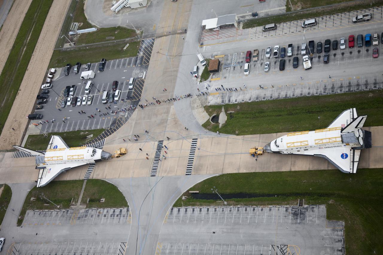 CAPE CANAVERAL, Fla. -- A unique glimpse of operations at NASA's Kennedy Space Center in Florida shows space shuttle Discovery, at right, approaching shuttle Endeavour outside Orbiter Processing Facility-3 (OPF-3). Discovery, which temporarily was being stored in the Vehicle Assembly Building (VAB), is switching places with Endeavour, which has been undergoing decommissioning in OPF-1. Both shuttles will stop briefly outside OPF-3 for a "nose-to-nose" photo opportunity. Discovery then will be rolled into OPF-1 and Endeavour into the VAB. The image was taken from the top of the VAB. In OPF-1, Discovery will undergo further preparations for public display at the Smithsonian's National Air and Space Museum Steven F. Udvar-Hazy Center in Virginia. Endeavour will be stored in the VAB until October when it will be moved into OPF-2 for further work to get it ready for public display at the California Science Center in Los Angeles. For more information, visit http://www.nasa.gov/shuttle. Photo credit: NASA/Frankie Martin