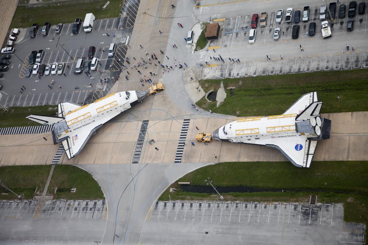 CAPE CANAVERAL, Fla. -- At NASA's Kennedy Space Center in Florida, space shuttle Discovery, at right, awaits its turn to approach shuttle Endeavour outside Orbiter Processing Facility-3 (OPF-3). Discovery, which temporarily was being stored in the Vehicle Assembly Building (VAB), is switching places with Endeavour, which has been undergoing decommissioning in OPF-1. Both shuttles will stop briefly outside OPF-3 for a "nose-to-nose" photo opportunity. Discovery then will be rolled into OPF-1 and Endeavour into the VAB. The image was taken from the top of the VAB. In OPF-1, Discovery will undergo further preparations for public display at the Smithsonian's National Air and Space Museum Steven F. Udvar-Hazy Center in Virginia. Endeavour will be stored in the VAB until October when it will be moved into OPF-2 for further work to get it ready for public display at the California Science Center in Los Angeles. For more information, visit http://www.nasa.gov/shuttle. Photo credit: NASA/Frankie Martin