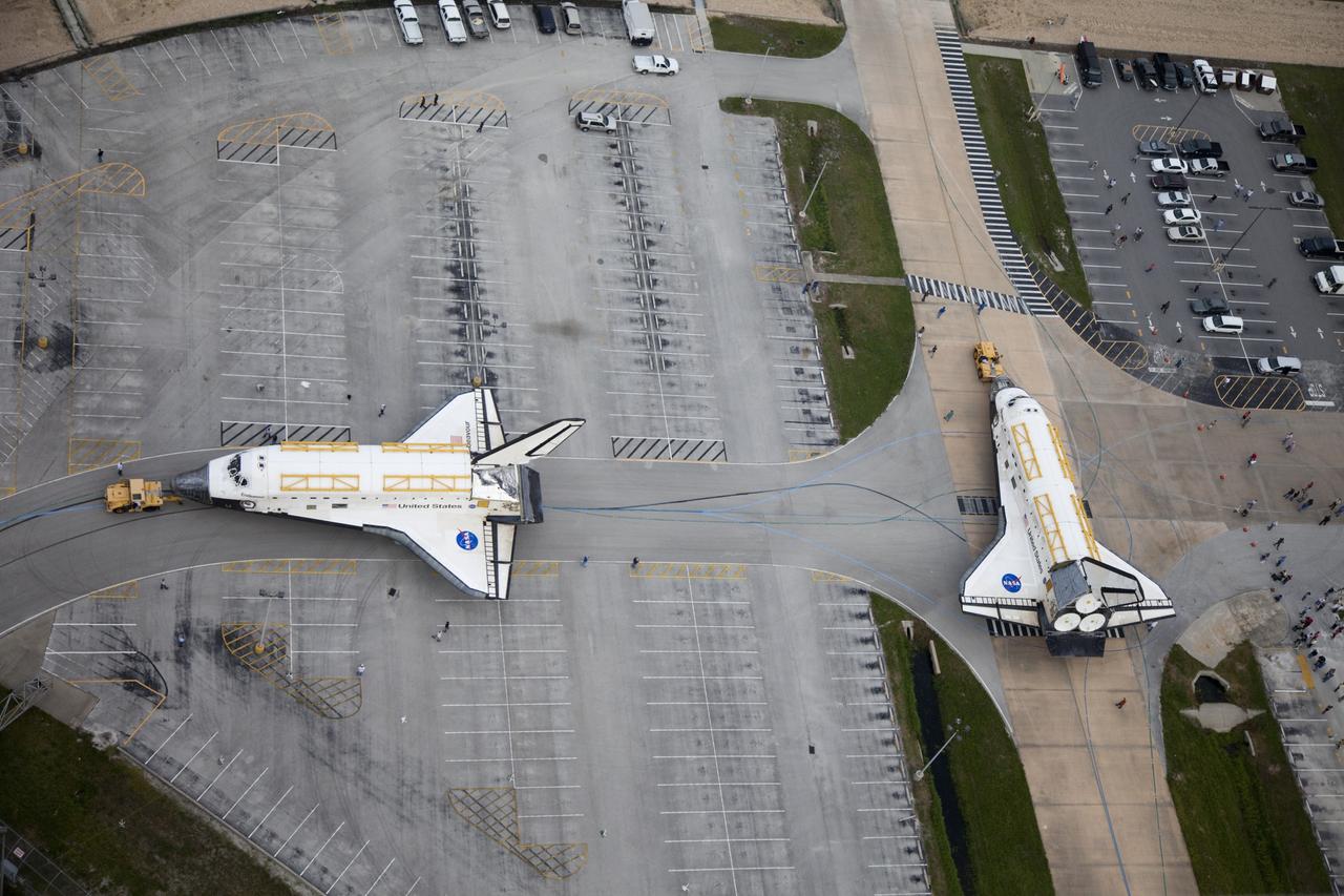 CAPE CANAVERAL, Fla. -- At NASA's Kennedy Space Center in Florida, space shuttles Discovery, at right, and Endeavour go their separate ways outside Orbiter Processing Facility-3 (OPF-3) where they paused for a unique "nose-to-nose" photo opportunity.  Discovery, which temporarily was being stored in the Vehicle Assembly Building (VAB), is switching places with Endeavour, which has been undergoing decommissioning in OPF-1.  Discovery will be rolled into OPF-1 and Endeavour into the VAB.      The image was taken from the top of the VAB.  In OPF-1, Discovery will undergo further preparations for public display at the Smithsonian's National Air and Space Museum Steven F. Udvar-Hazy Center in Virginia. Endeavour will be stored in the VAB until October when it will be moved into OPF-2 for further work to get it ready for public display at the California Science Center in Los Angeles.  For more information, visit http://www.nasa.gov/shuttle. Photo credit: NASA/Frankie Martin