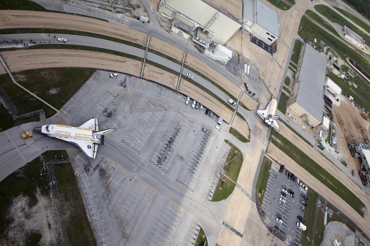 CAPE CANAVERAL, Fla. -- At NASA's Kennedy Space Center in Florida, space shuttles Discovery, at right, and Endeavour switch places. The shuttles stopped briefly outside Orbiter Processing Facility-3 (OPF-3) for a unique "nose-to-nose" photo opportunity.  Discovery, which temporarily was being stored in the Vehicle Assembly Building (VAB), is swapping places with Endeavour, which has been undergoing decommissioning in OPF-1.  Discovery will be rolled into OPF-1 and Endeavour into the VAB.    The image was taken from the top of the VAB.  In OPF-1, Discovery will undergo further preparations for public display at the Smithsonian's National Air and Space Museum Steven F. Udvar-Hazy Center in Virginia. Endeavour will be stored in the VAB until October when it will be moved into OPF-2 for further work to get it ready for public display at the California Science Center in Los Angeles.  For more information, visit http://www.nasa.gov/shuttle. Photo credit: NASA/Frankie Martin