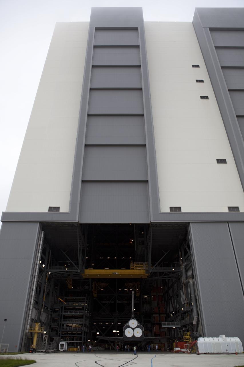 CAPE CANAVERAL, Fla. -- Seen through the open bay door of the Vehicle Assembly Building (VAB) at NASA's Kennedy Space Center in Florida, space shuttle Discovery is being prepared for its move to Orbiter Processing Facility-1 (OPF-1).  Discovery is switching places with shuttle Endeavour which has been undergoing decommissioning activities in OPF-1.  Both shuttles will stop briefly outside OPF-3 for a "nose-to-nose" photo opportunity. Discovery then will be rolled into OPF-1 and Endeavour into the VAB.    In OPF-1, Discovery will undergo further preparations for public display at the Smithsonian's National Air and Space Museum Steven F. Udvar-Hazy Center in Virginia. Endeavour will be stored in the VAB until October when it will be moved into OPF-2 for further work to get it ready for public display at the California Science Center in Los Angeles.  For more information, visit http://www.nasa.gov/shuttle. Photo credit: NASA/Dimitri Gerondidakis