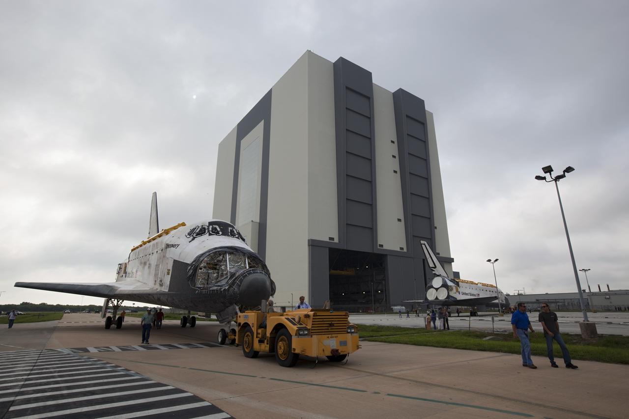 CAPE CANAVERAL, Fla. -- At NASA's Kennedy Space Center in Florida, space shuttle Discovery continues its trip to  Orbiter Processing Facility-1 (OPF-1) after stopping for a unique "nose-to-nose" photo opportunity outside OPF-3 with shuttle Endeavour.  Endeavour nears the open bay door of the Vehicle Assembly Building (VAB), at right.  Discovery, which temporarily was being stored in the VAB, is switching places with Endeavour, which has been undergoing decommissioning in OPF-1.    In OPF-1, Discovery will undergo further preparations for public display at the Smithsonian's National Air and Space Museum Steven F. Udvar-Hazy Center in Virginia. Endeavour will be stored in the VAB until October when it will be moved into OPF-2 for further work to get it ready for public display at the California Science Center in Los Angeles.  For more information, visit http://www.nasa.gov/shuttle. Photo credit: NASA/Dimitri Gerondidakis