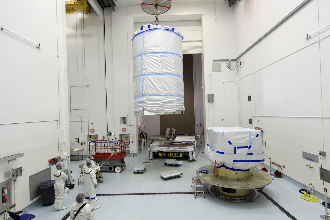 CAPE CANAVERAL, Fla. -- At Astrotech Space Operation's payload processing facility in Titusville, Fla., a crane lifts the protective canister that will enclose NASA's twin Gravity Recovery and Interior Laboratory spacecraft, at right, during transport to the launch pad.  The lunar probes are attached to a spacecraft adapter ring in their side-by-side launch configuration and wrapped in plastic to prevent contamination outside the clean room.    The spacecraft will fly in tandem orbits around the moon for several months to measure its gravity field. GRAIL's primary science objectives are to determine the structure of the lunar interior, from crust to core, and to advance understanding of the thermal evolution of the moon.  Launch aboard a United Launch Alliance Delta II rocket from Space Launch Complex 17B on Cape Canaveral Air Force Station is scheduled for Sept. 8.  For more information, visit http://www.nasa.gov/grail. Photo credit: NASA/Jim Grossmann