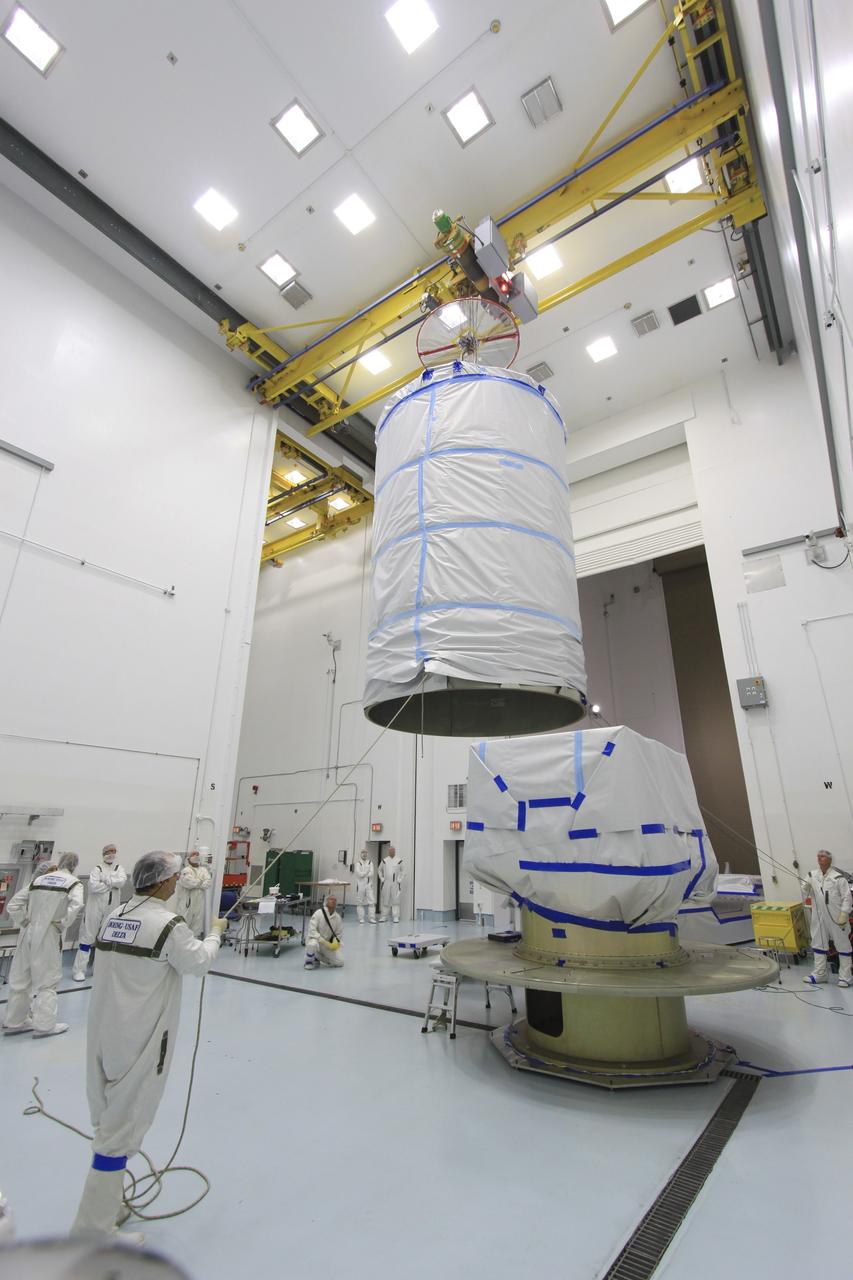 CAPE CANAVERAL, Fla. -- At Astrotech Space Operation's payload processing facility in Titusville, Fla., a crane lowers a protective canister toward NASA's twin Gravity Recovery and Interior Laboratory spacecraft during preparations to transport them to the launch pad.  The lunar probes are attached to a spacecraft adapter ring in their side-by-side launch configuration and wrapped in plastic to prevent contamination outside the clean room.  The spacecraft will fly in tandem orbits around the moon for several months to measure its gravity field. GRAIL's primary science objectives are to determine the structure of the lunar interior, from crust to core, and to advance understanding of the thermal evolution of the moon.  Launch aboard a United Launch Alliance Delta II rocket from Space Launch Complex 17B on Cape Canaveral Air Force Station is scheduled for Sept. 8.  For more information, visit http://www.nasa.gov/grail. Photo credit: NASA/Jim Grossmann