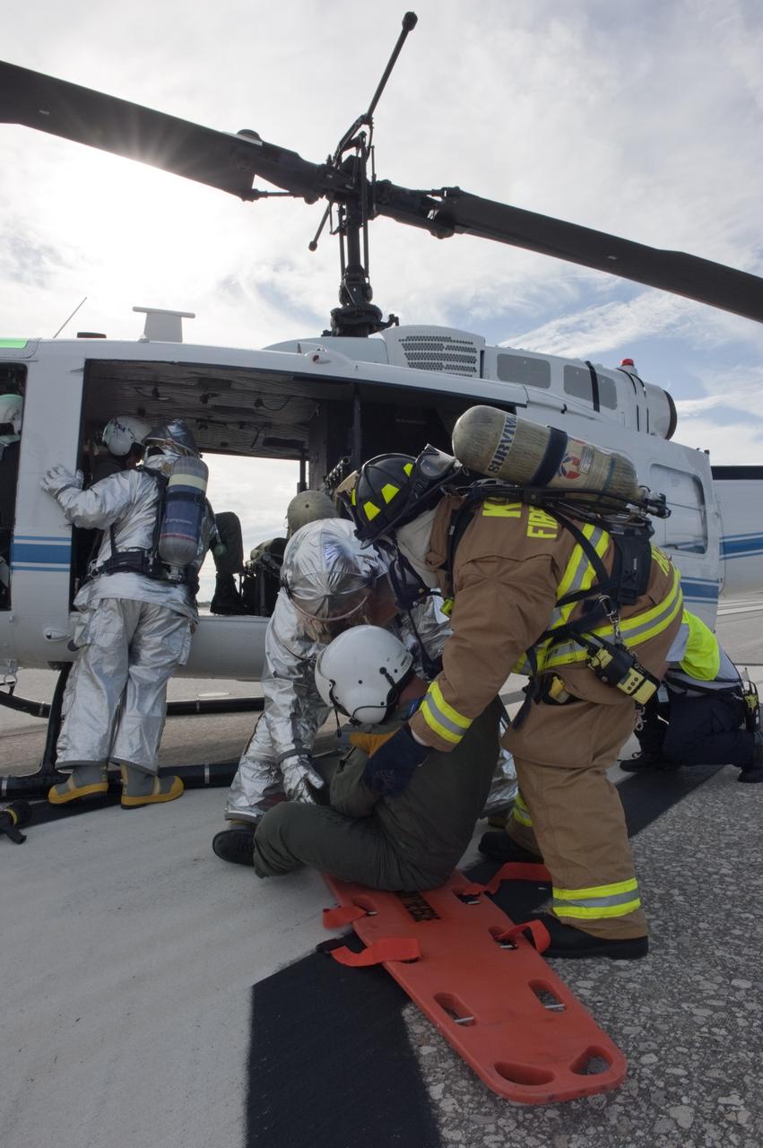 CAPE CANAVERAL, Fla. -- NASA Fire Rescue personnel assist volunteers portraying injured Huey II helicopter crew members participating in the aviation safety exercise during Emergency Response Safety Training at the Shuttle Landing Facility, Runway 33, at NASA’s Kennedy Space Center in Florida.    The simulated helicopter mishap exercise was conducted to evaluate emergency response and mishap investigations of aircraft at Kennedy. Participants included Air Rescue Fire Fighters, Flight Operations, Disaster Preparedness, Security, and Safety. NASA mandates simulated aviation safety training take place every two years. Photo credit: NASA/Kim Shiflett