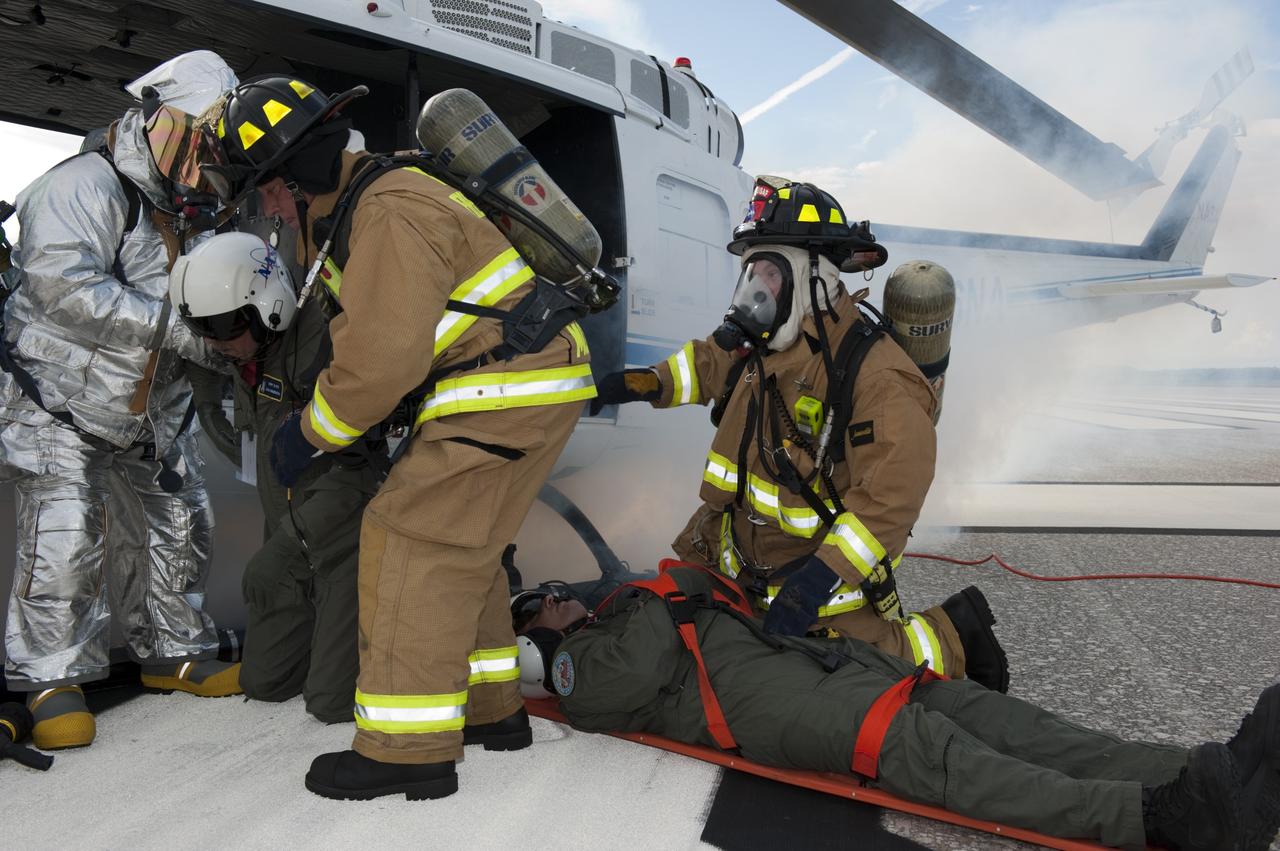 CAPE CANAVERAL, Fla. -- NASA Fire Rescue personnel assist volunteers portraying injured Huey II helicopter crew members participating in the aviation safety exercise during Emergency Response Safety Training at the Shuttle Landing Facility, Runway 33, at NASA’s Kennedy Space Center in Florida.    The simulated helicopter mishap exercise was conducted to evaluate emergency response and mishap investigations of aircraft at Kennedy. Participants included Air Rescue Fire Fighters, Flight Operations, Disaster Preparedness, Security, and Safety. NASA mandates simulated aviation safety training take place every two years. Photo credit: NASA/Kim Shiflett